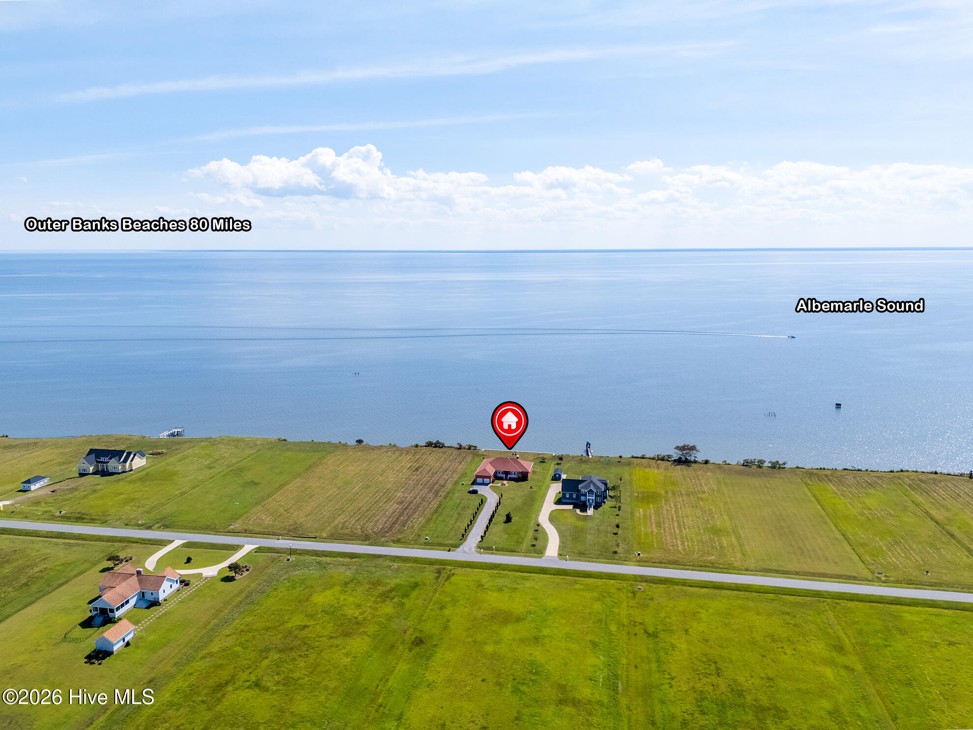 Aerial view of a waterfront home marked beside Albemarle Sound, with open grassy lots along the shoreline.