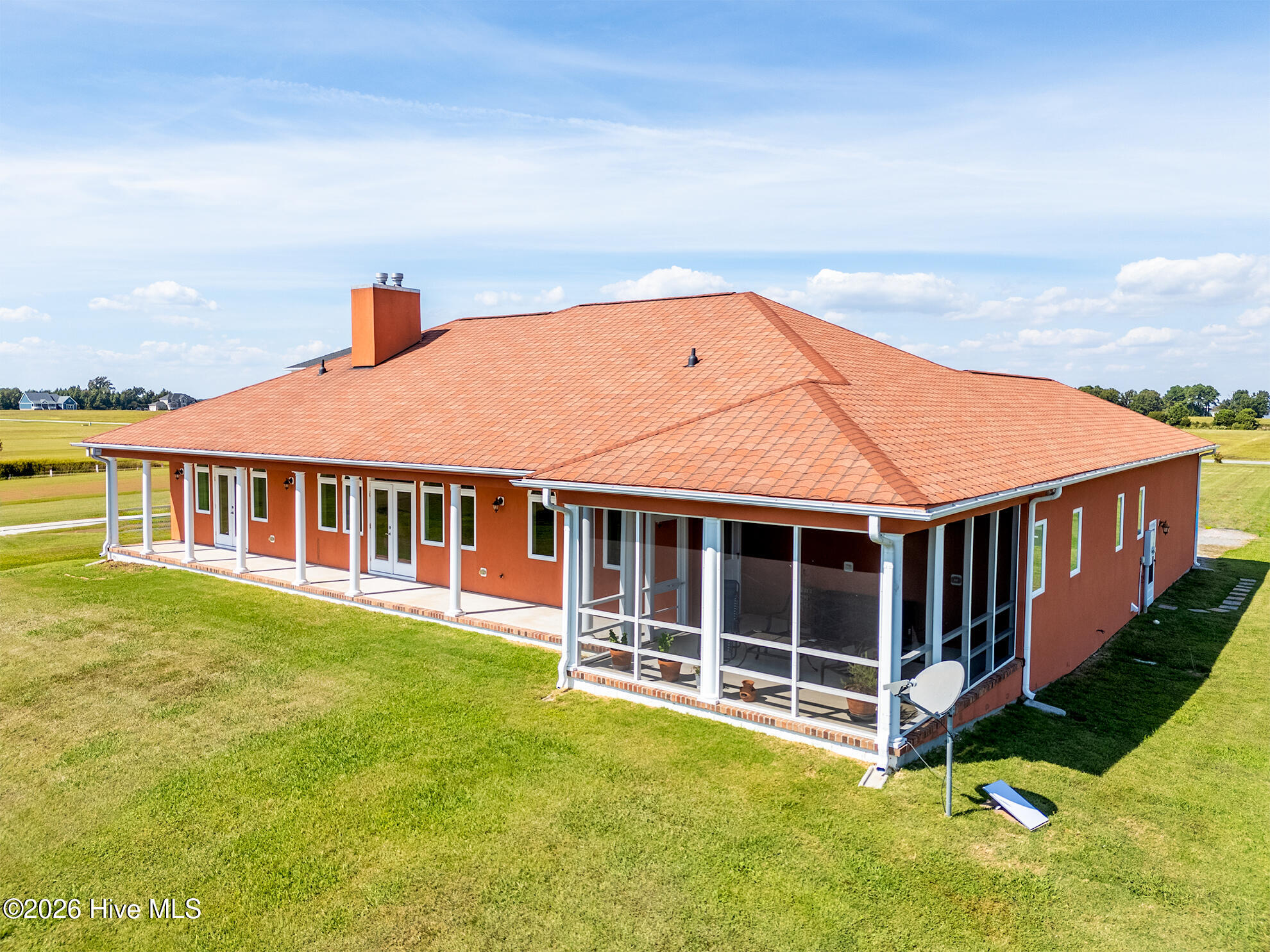 Single-story red-orange home with a terracotta tile roof, white trim, and a screened porch, viewed from above.