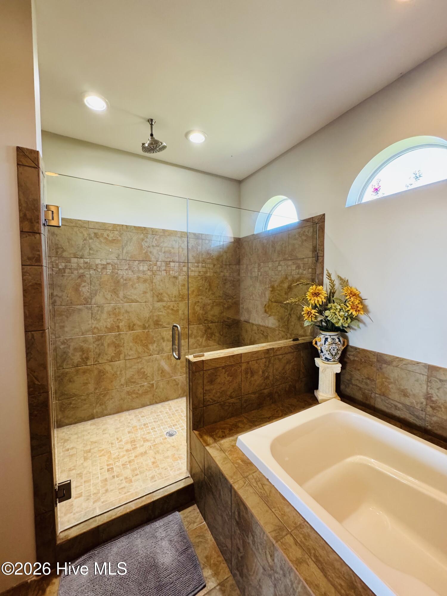 Bathroom with a glass-enclosed tiled shower beside a built-in soaking tub.