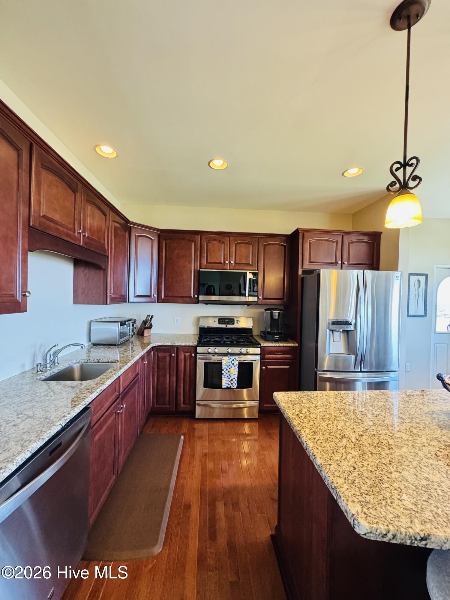 Kitchen with cherry cabinets, granite counters, a large island, and stainless steel appliances.