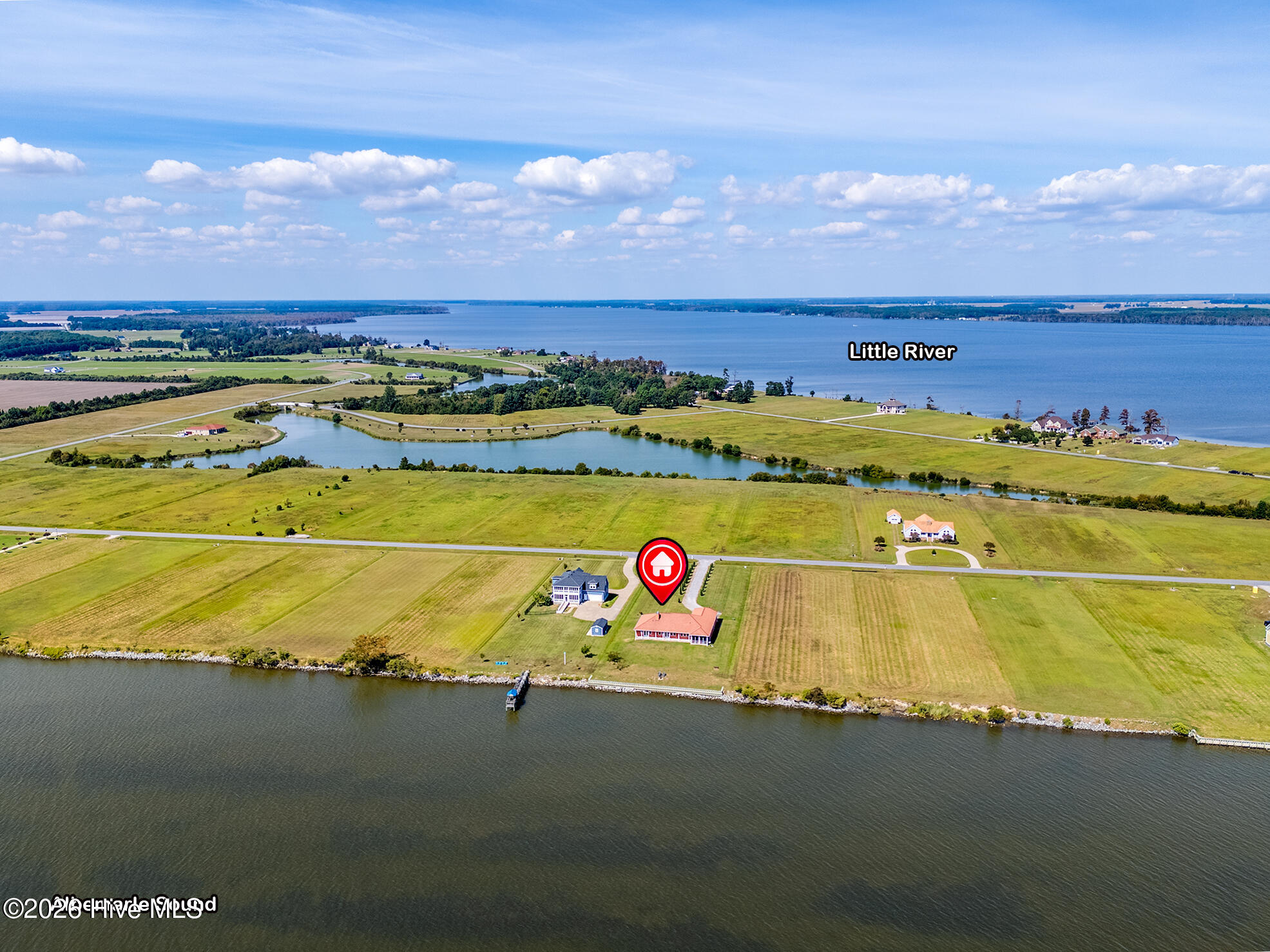 Aerial view of the marked waterfront property, with open fields, a shoreline dock, and Little River beyond.