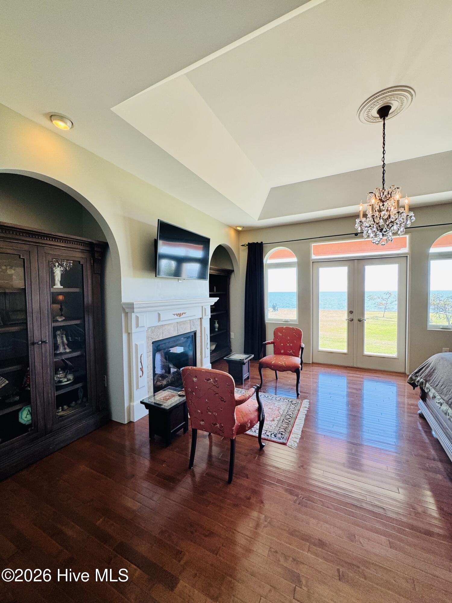 Furnished living room with a white fireplace and water views through glass doors.