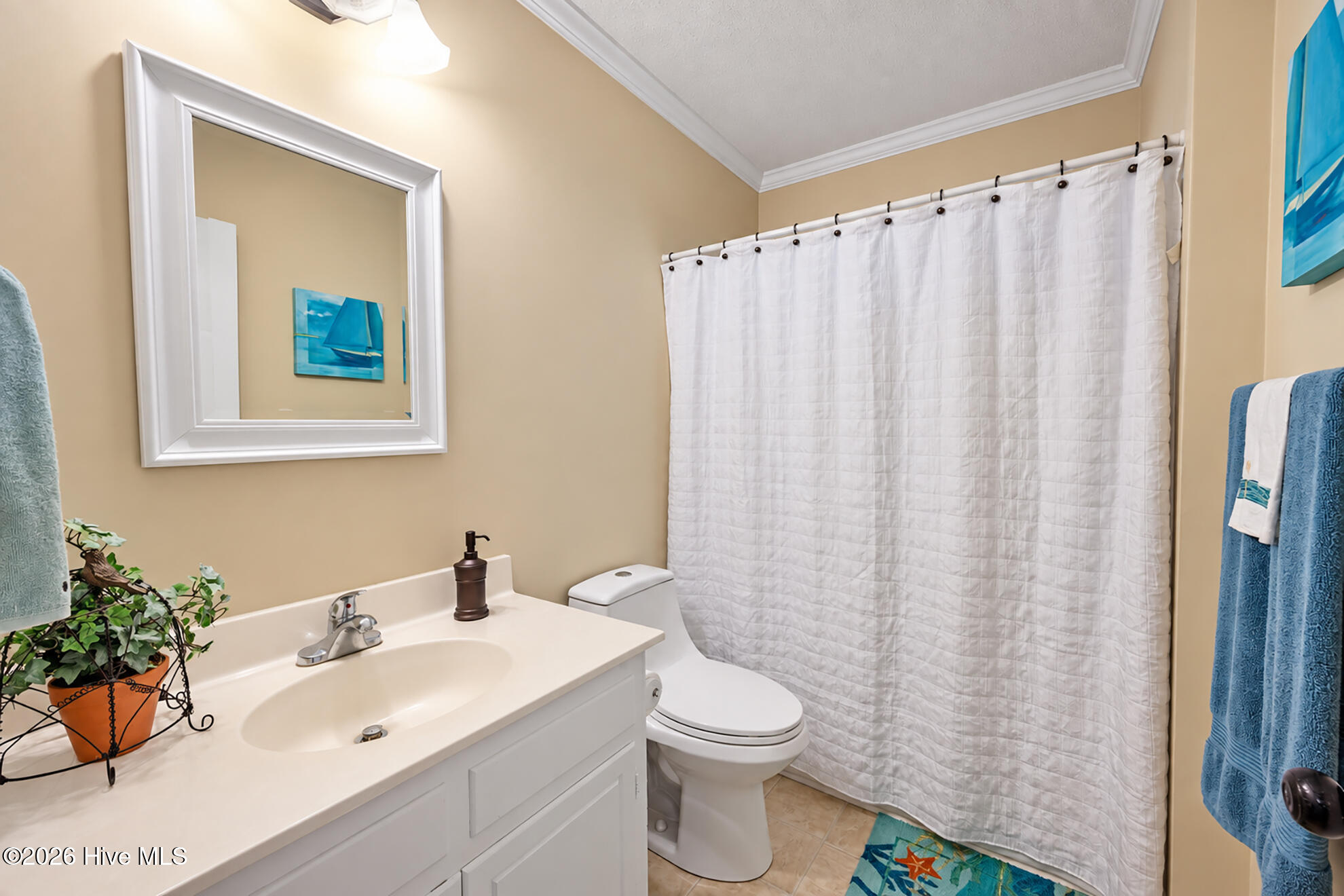 Bathroom with a white vanity, quilted shower curtain, and blue coastal accents.
