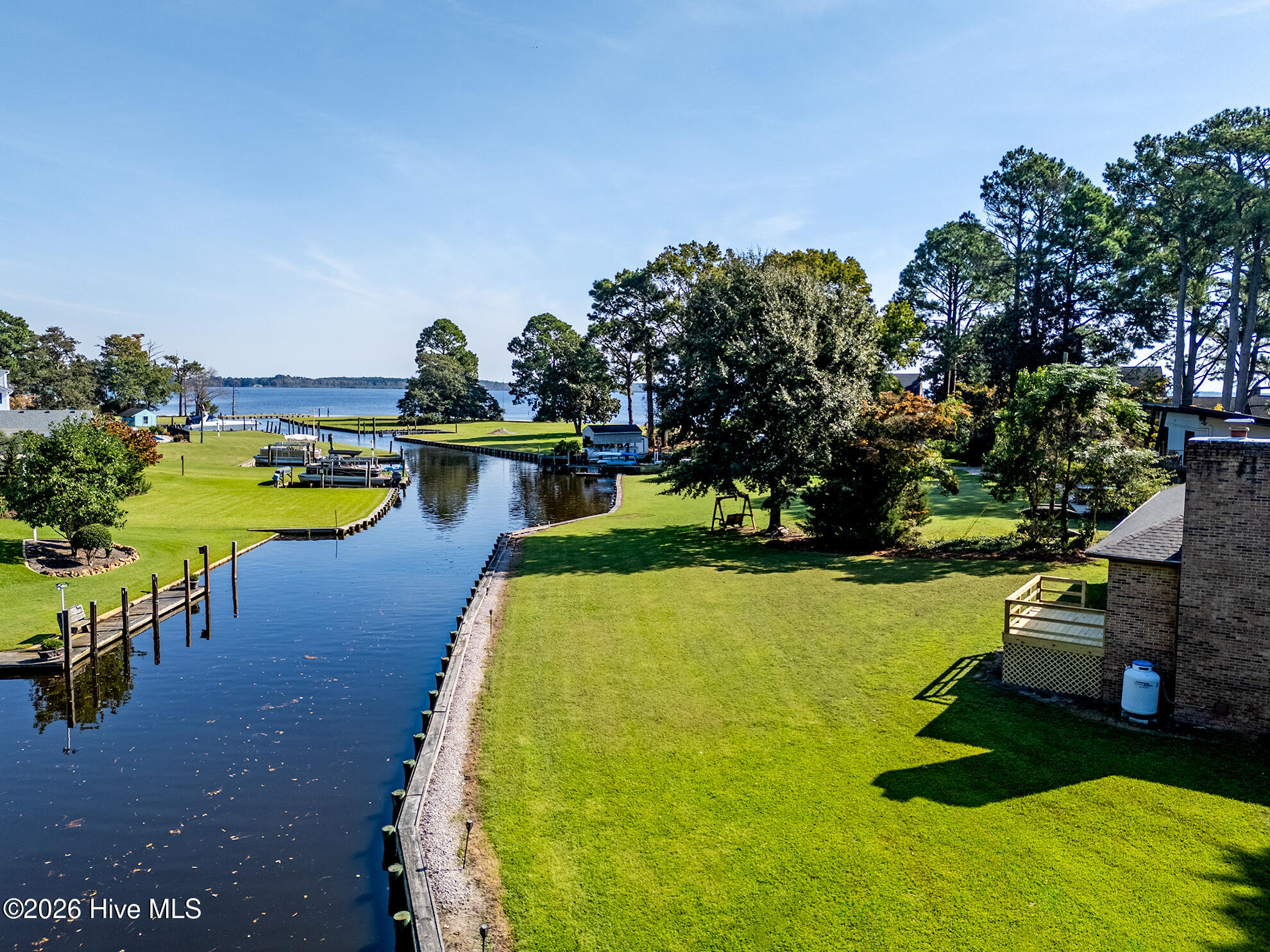 Waterfront property with a canal, docks, broad lawn, and river beyond.