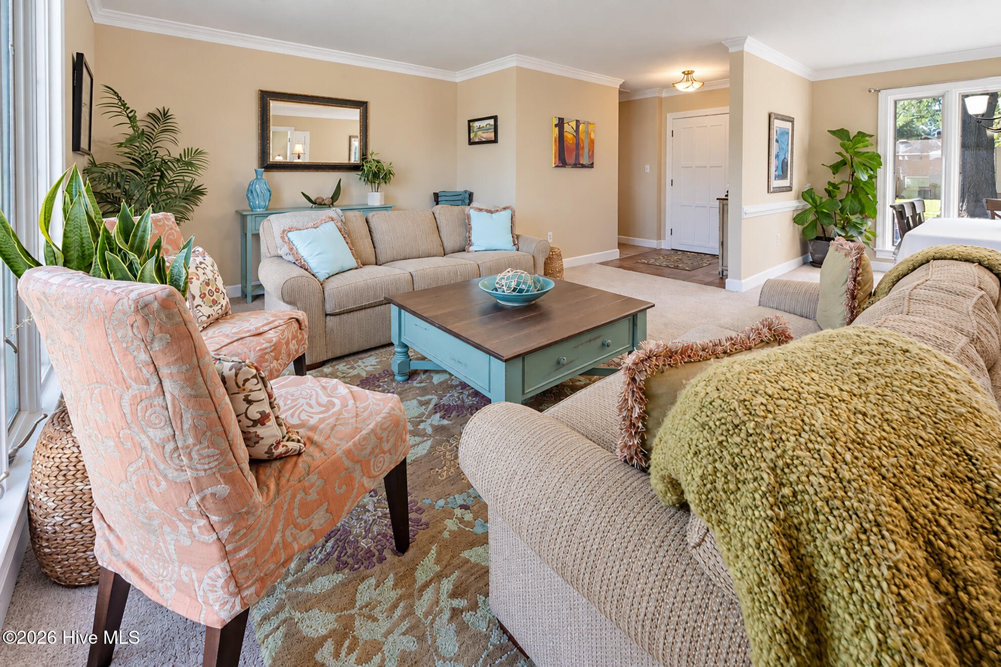 Living room with beige sofas, peach-patterned armchairs, and a turquoise coffee table.