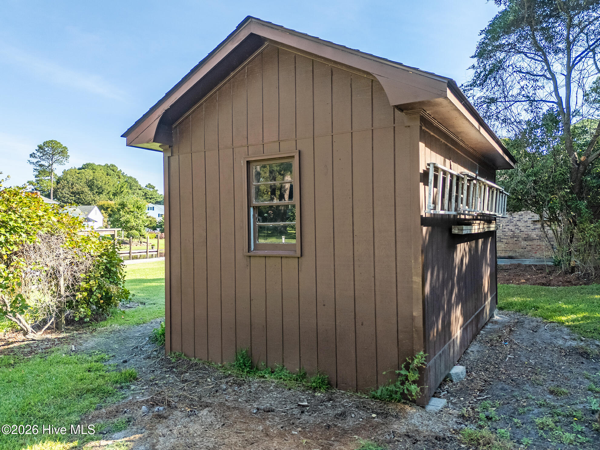 Brown detached outbuilding with a single window and a narrow raised walkway with railing.