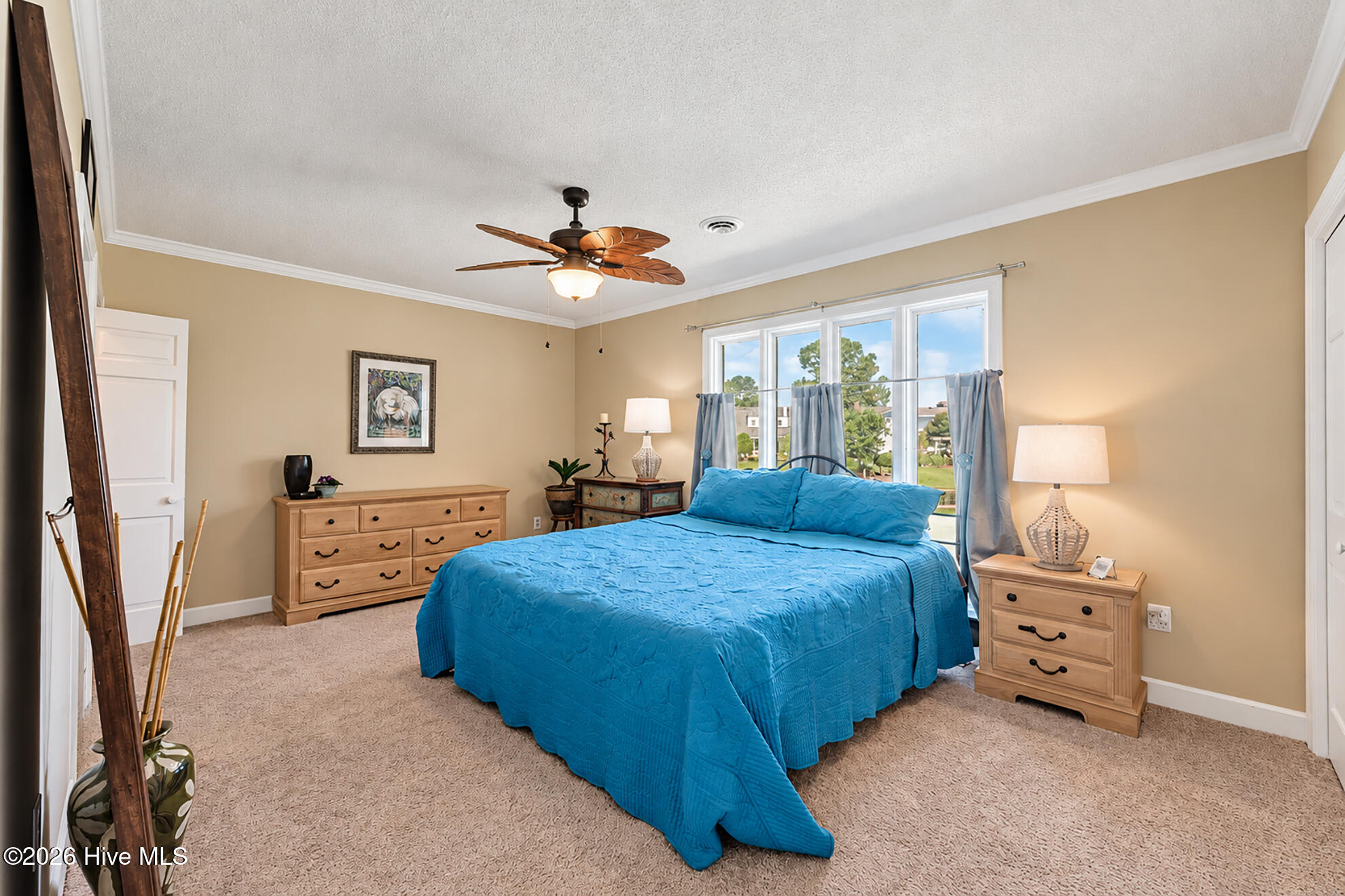 Bedroom with a large bed in bright blue bedding and a wide curtained window.