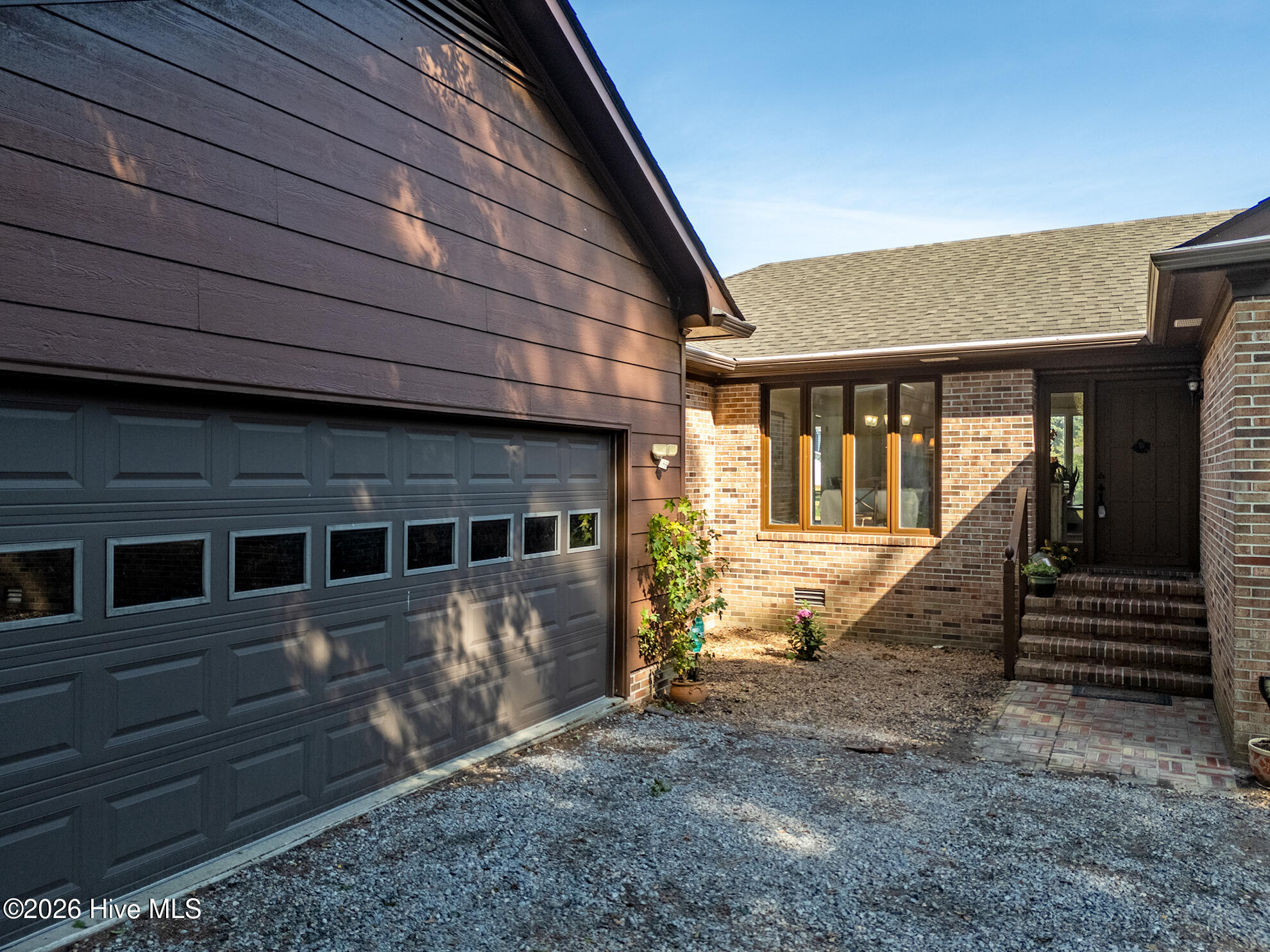 Home exterior with a windowed garage door, brick facade, and recessed front entry.