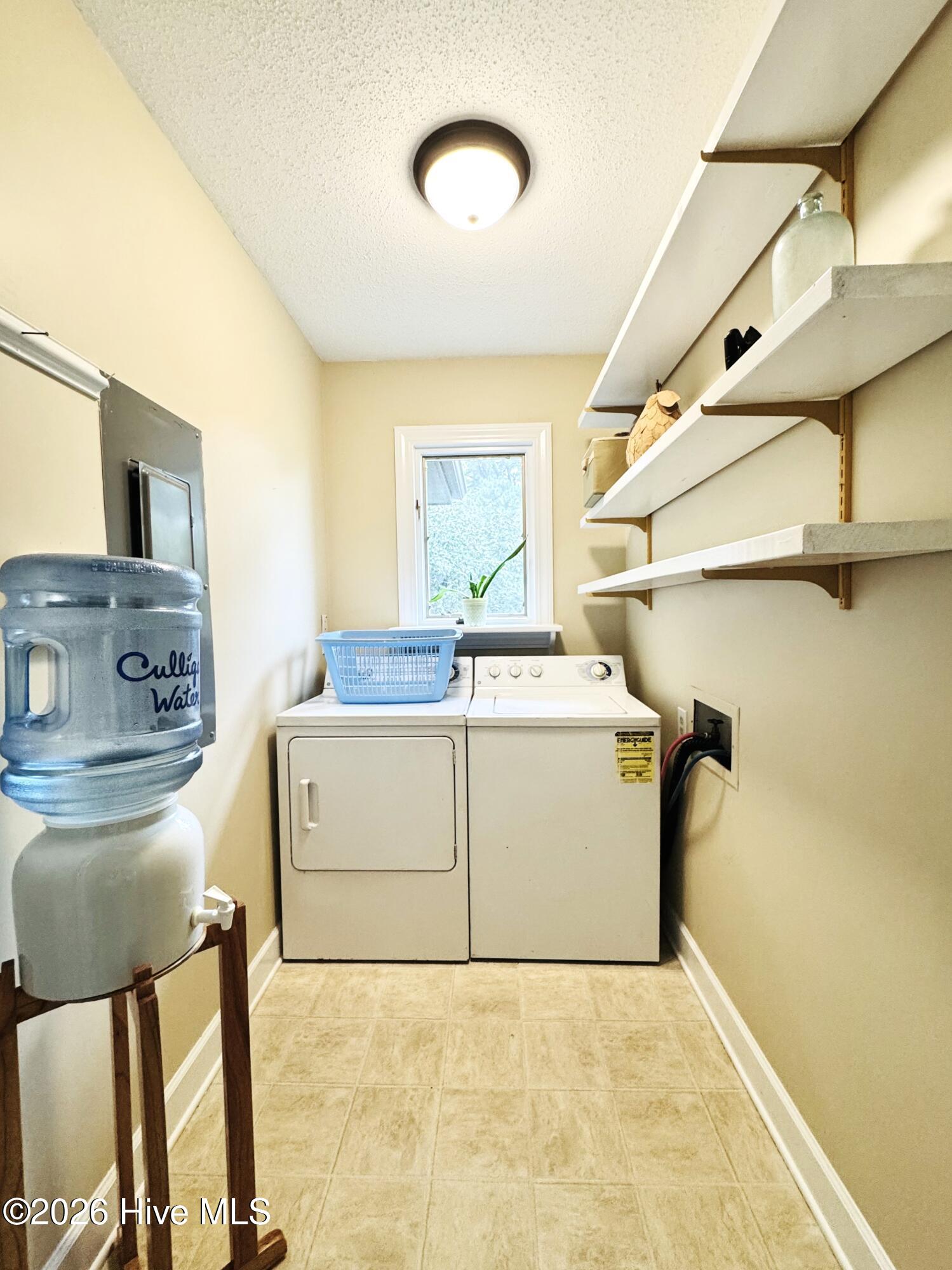 Laundry room with washer and dryer, open shelves, and a Culligan water dispenser.