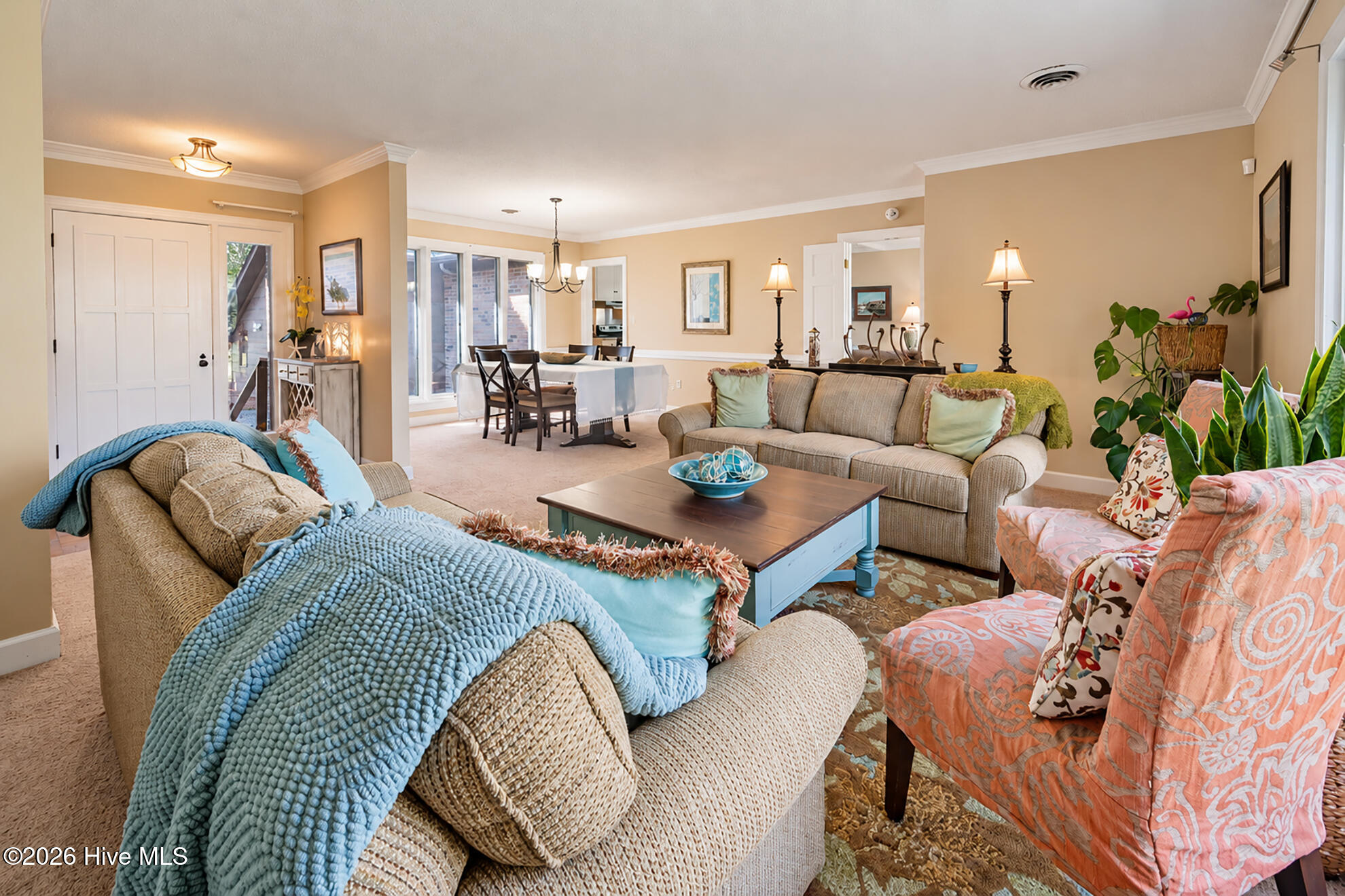 Living room with beige sofas, coral-patterned armchairs, and an adjoining dining area.
