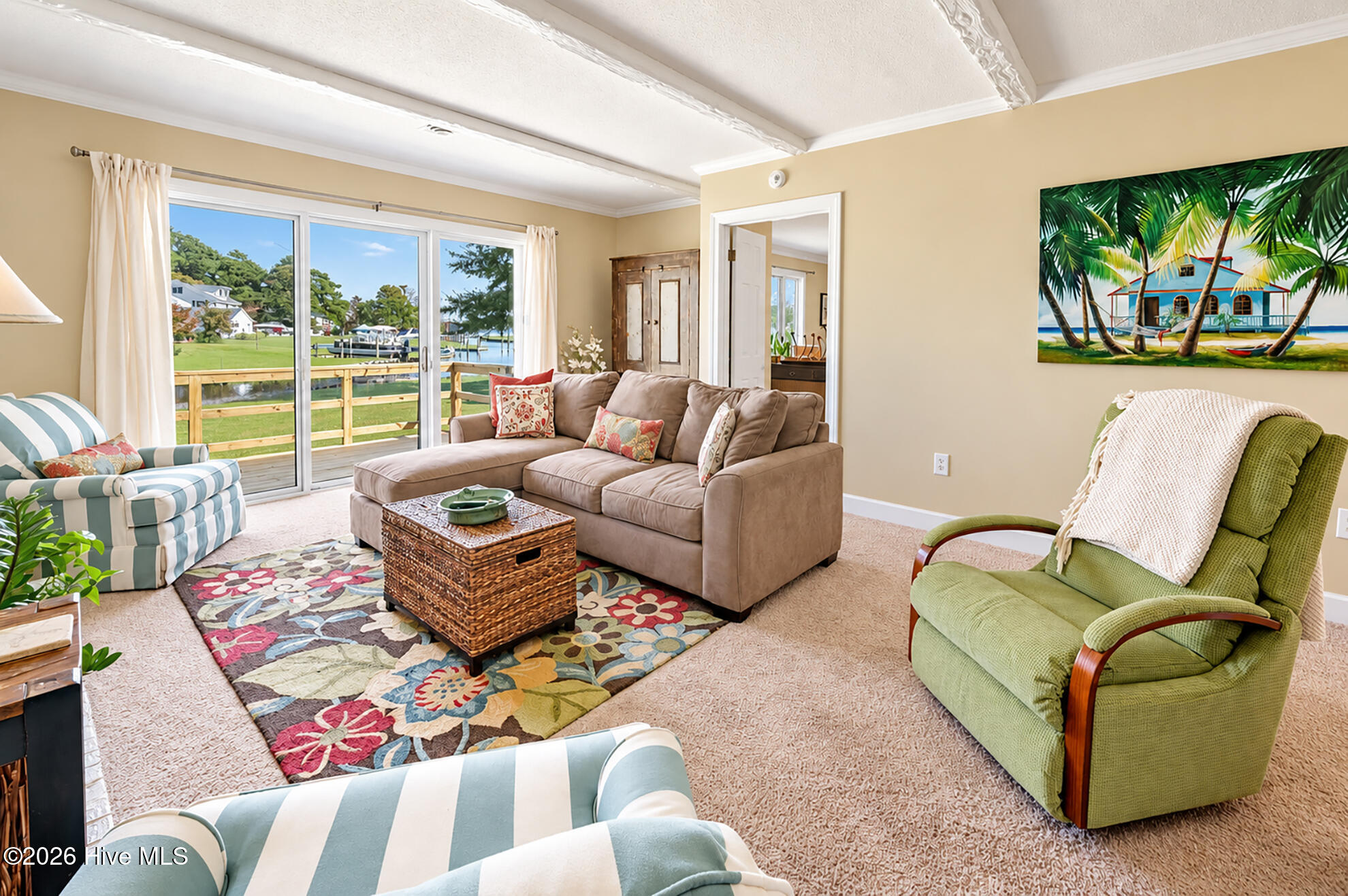 Living room with a colorful floral rug and water view through sliding glass doors.