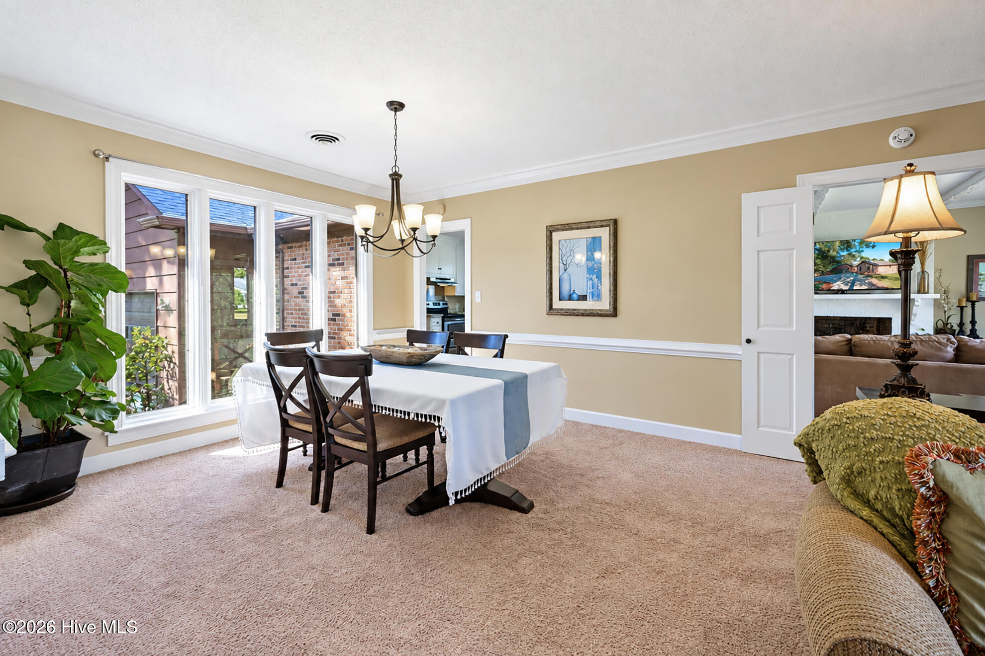 Dining room with a table by large windows and an open doorway to the living room.