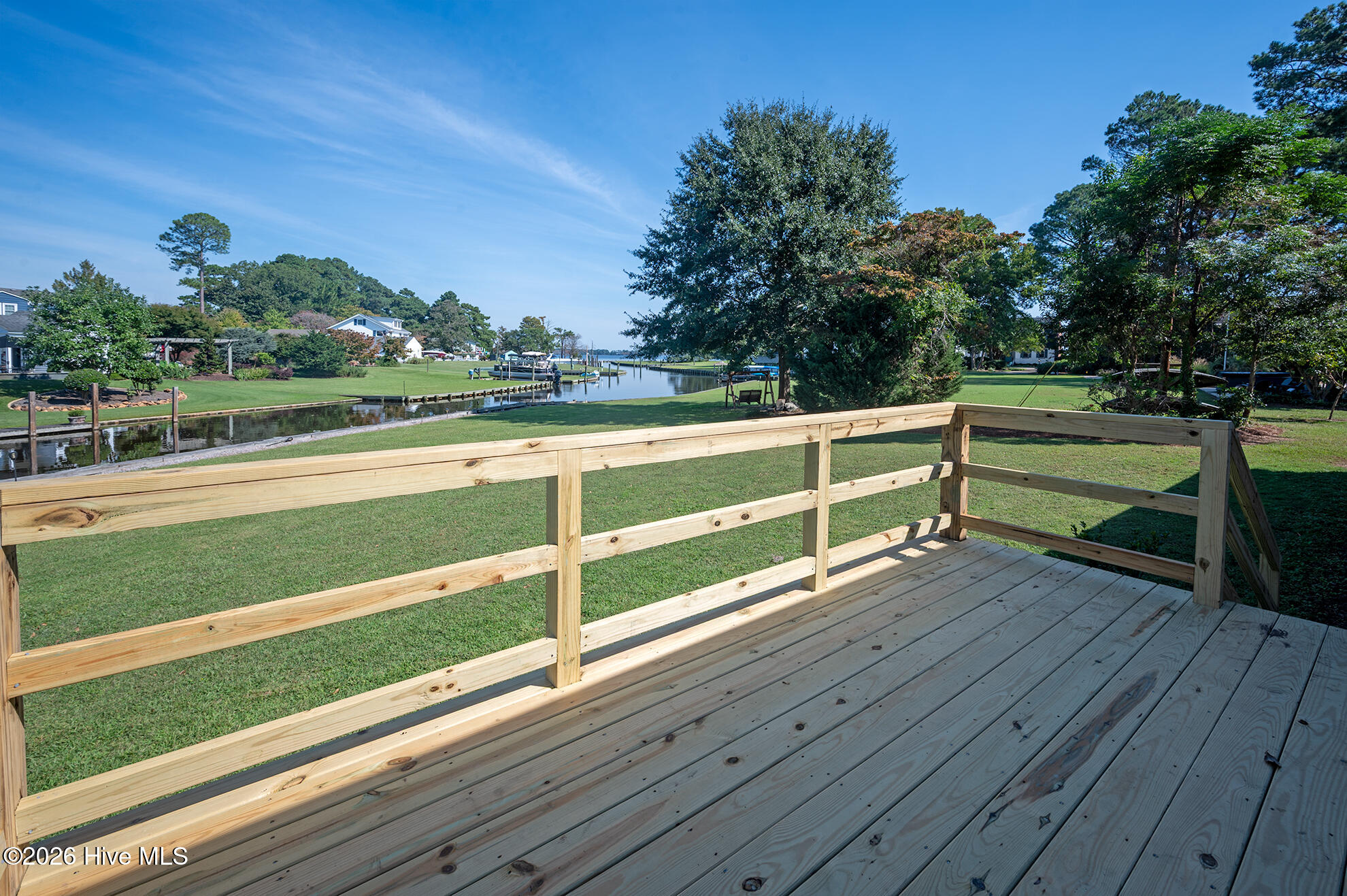 Rear deck overlooking a canal, with a broad lawn and neighboring waterfront homes.