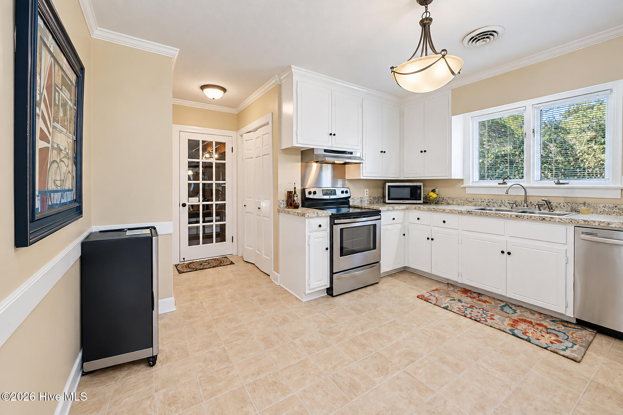Kitchen with white cabinets, stainless steel appliances, and a sink beneath a wide window.