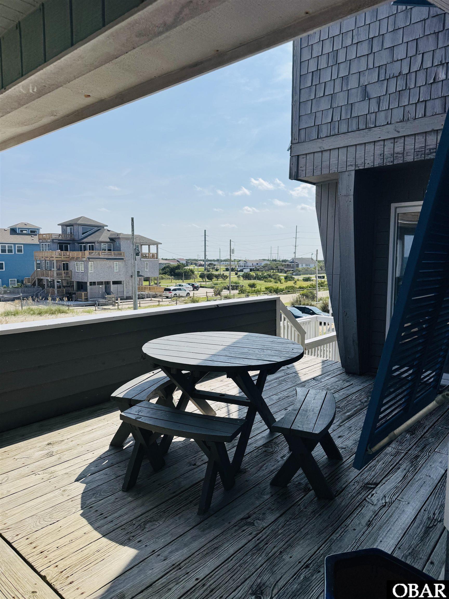 Wooden deck with a round picnic table overlooking neighboring coastal homes.