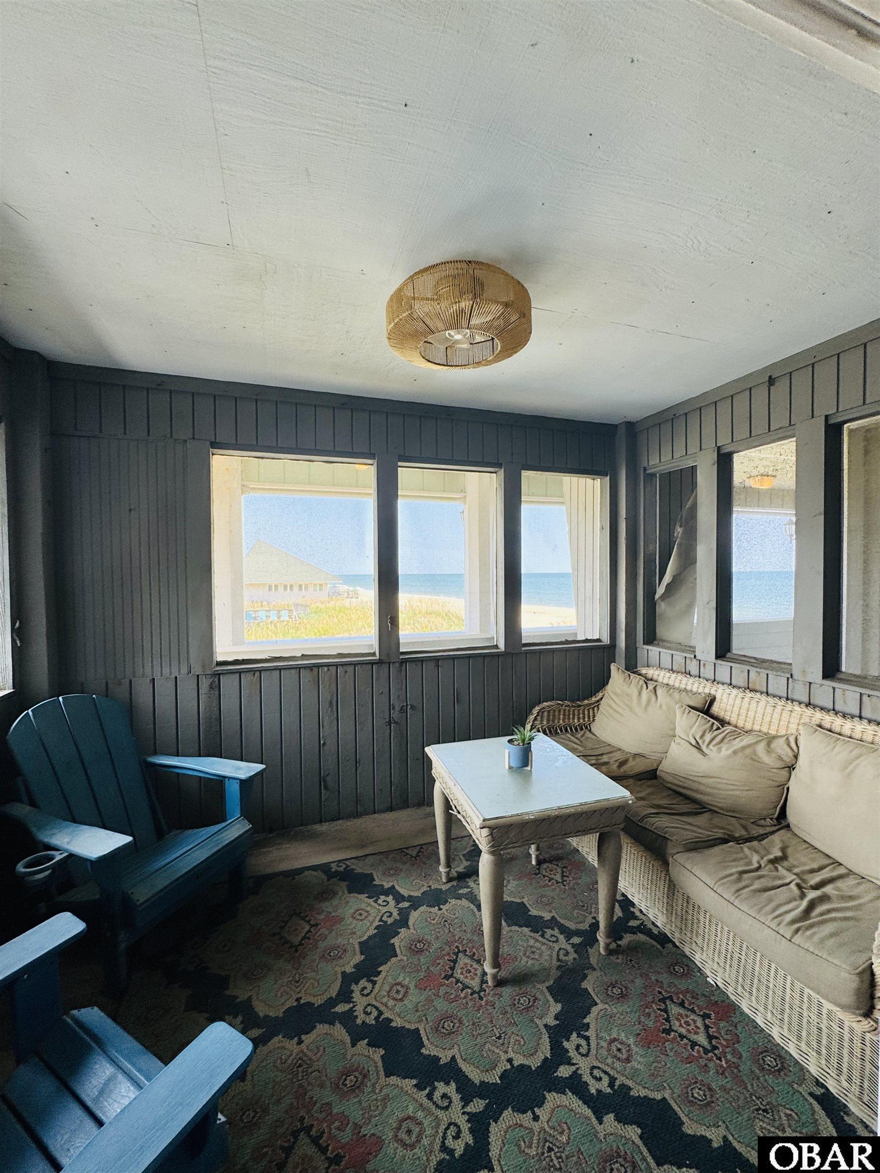 Enclosed porch with wicker seating and ocean views through the windows.