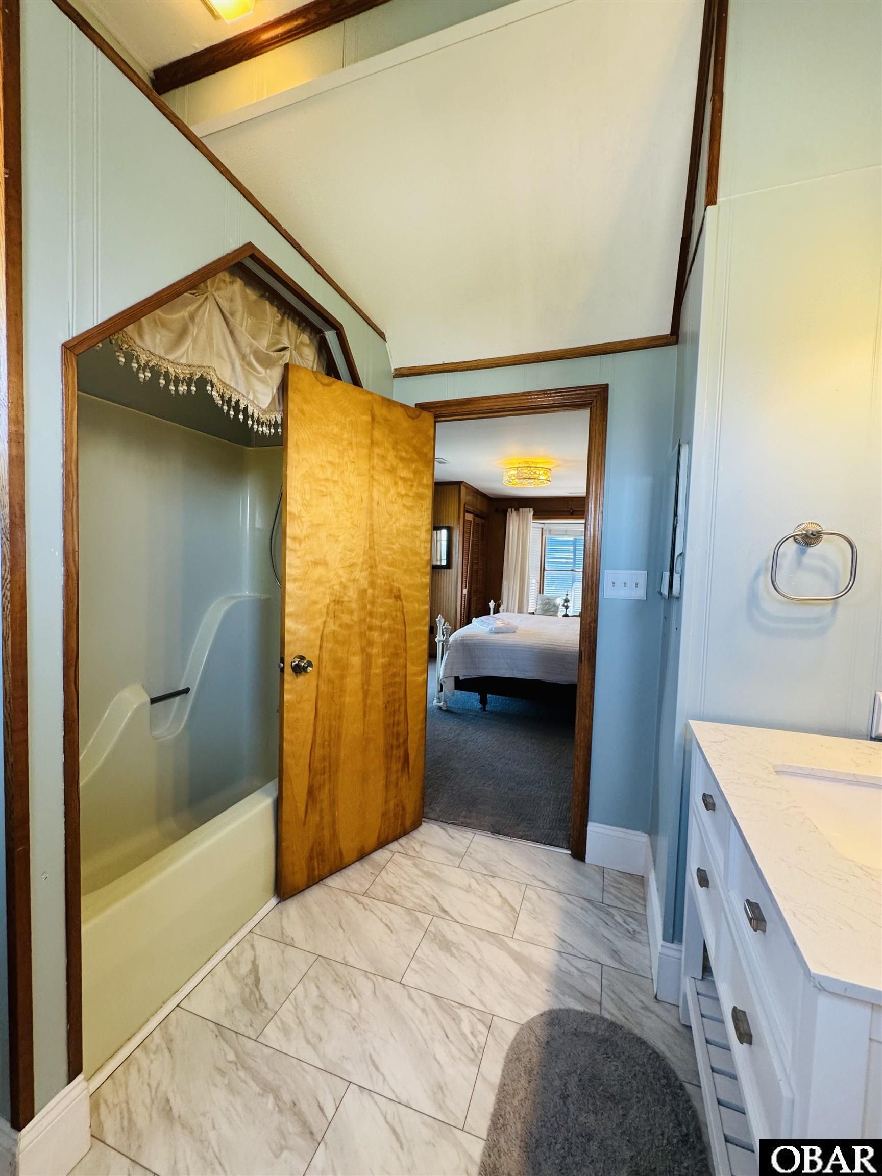 Bathroom with glass shower, white vanity, and an open doorway to a bedroom.