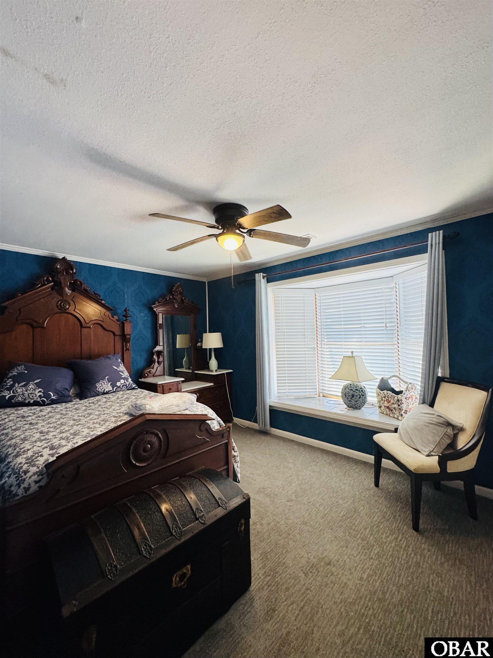 Bedroom with ornate dark wood furniture, deep blue walls, and a large window with white blinds.