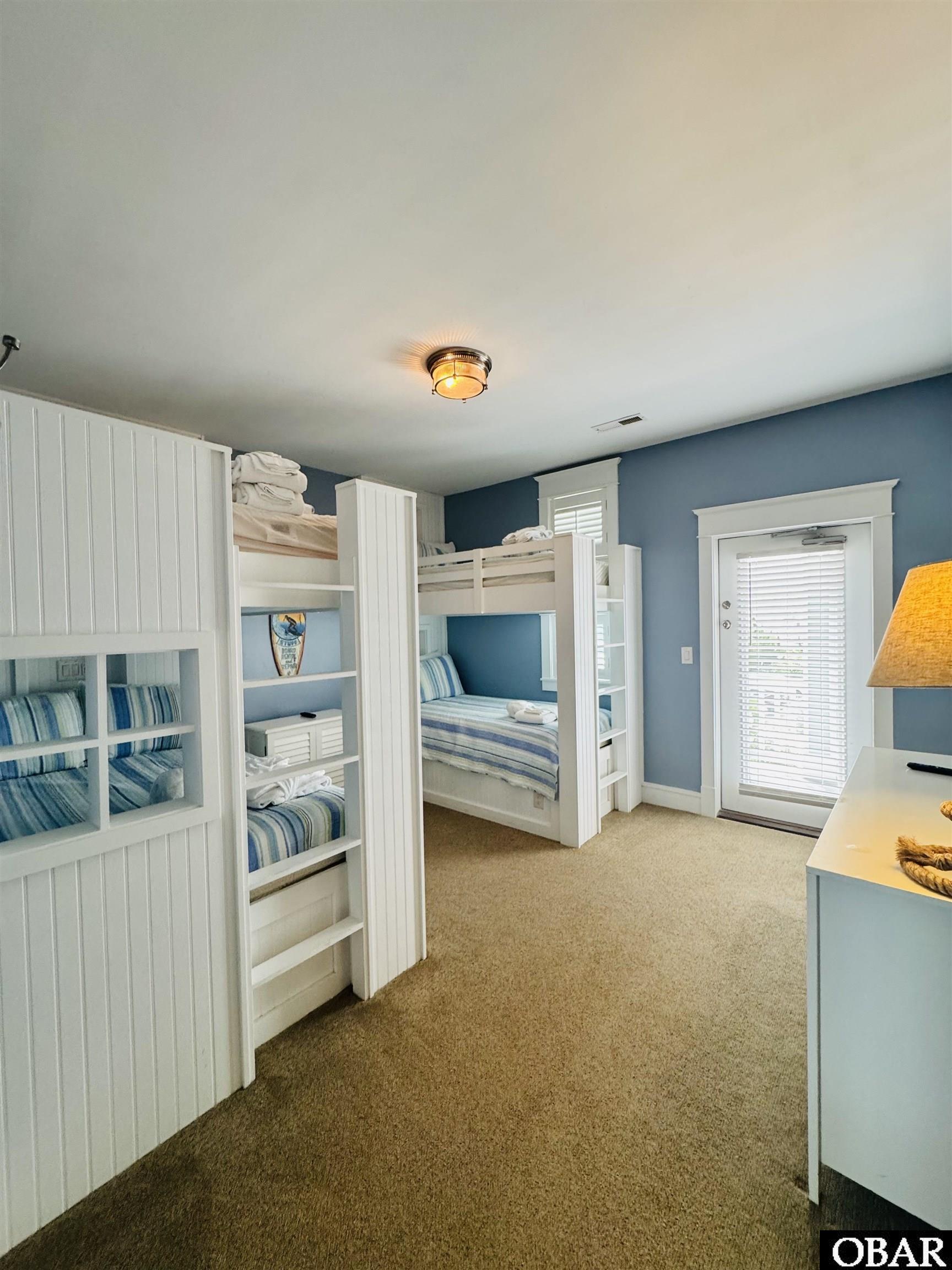 Bedroom with white built-in bunk beds and blue-and-white striped bedding.