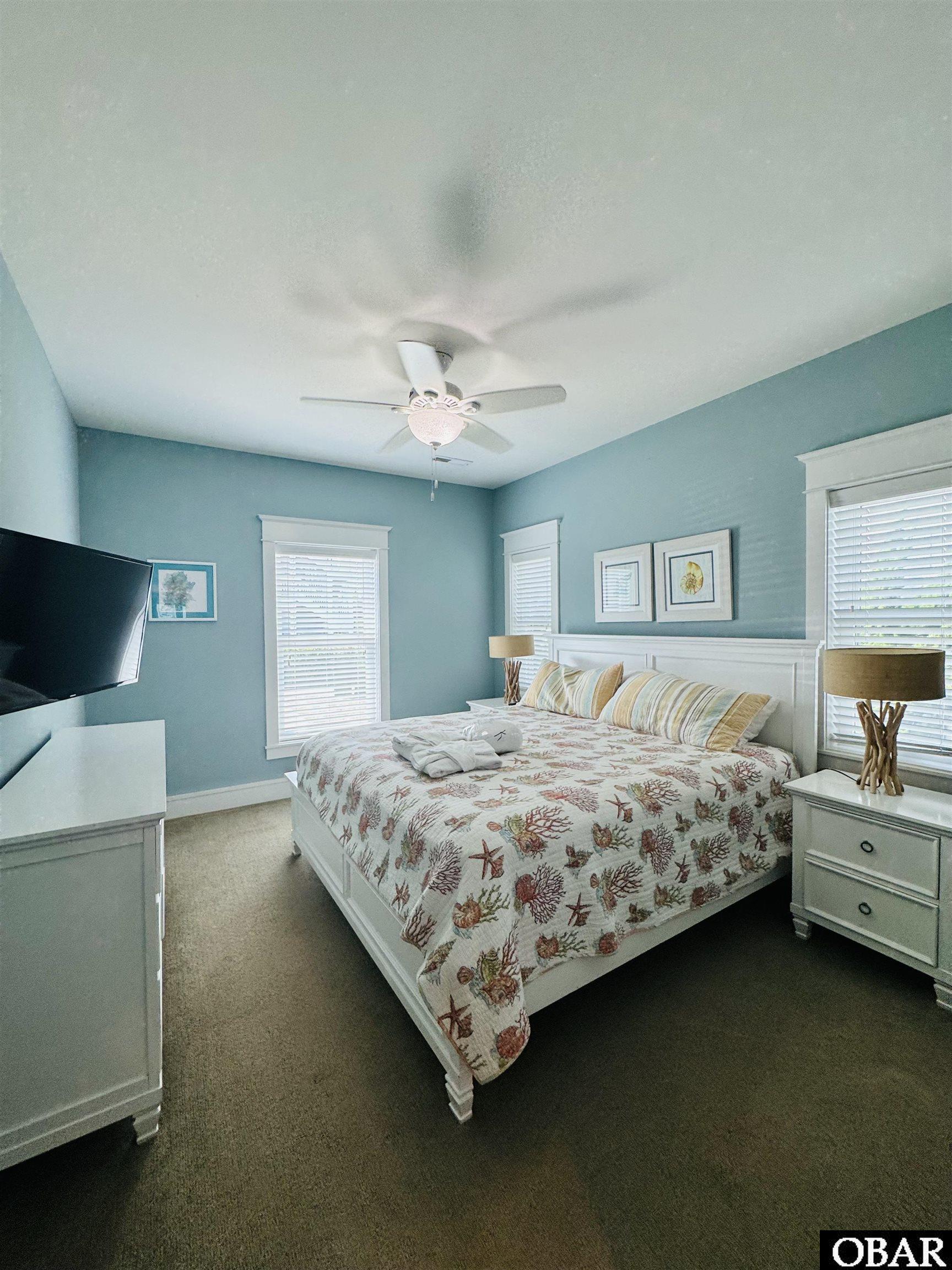 Bedroom with blue walls, white furnishings, and a sea-life patterned bedspread.