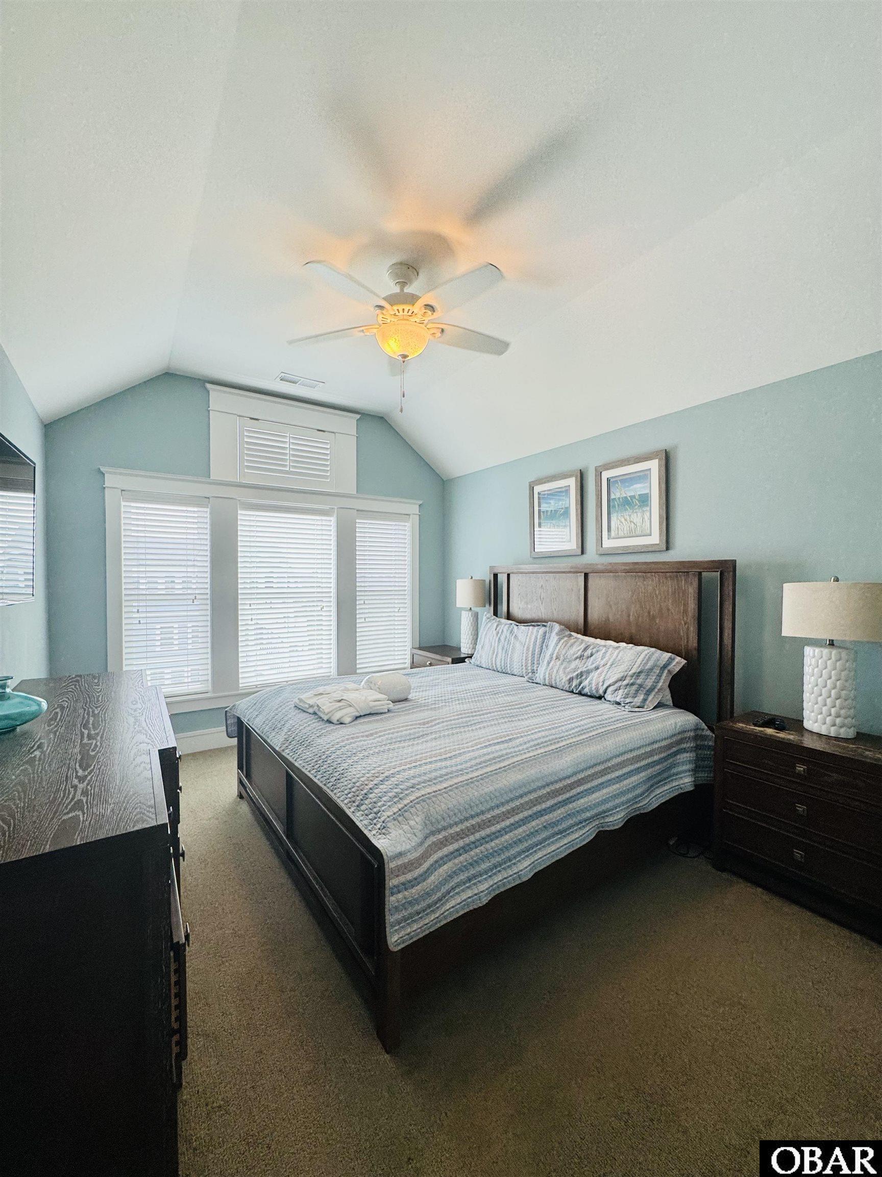 Bedroom with a dark wood bed, blue striped bedding, aqua walls, and vaulted ceiling.