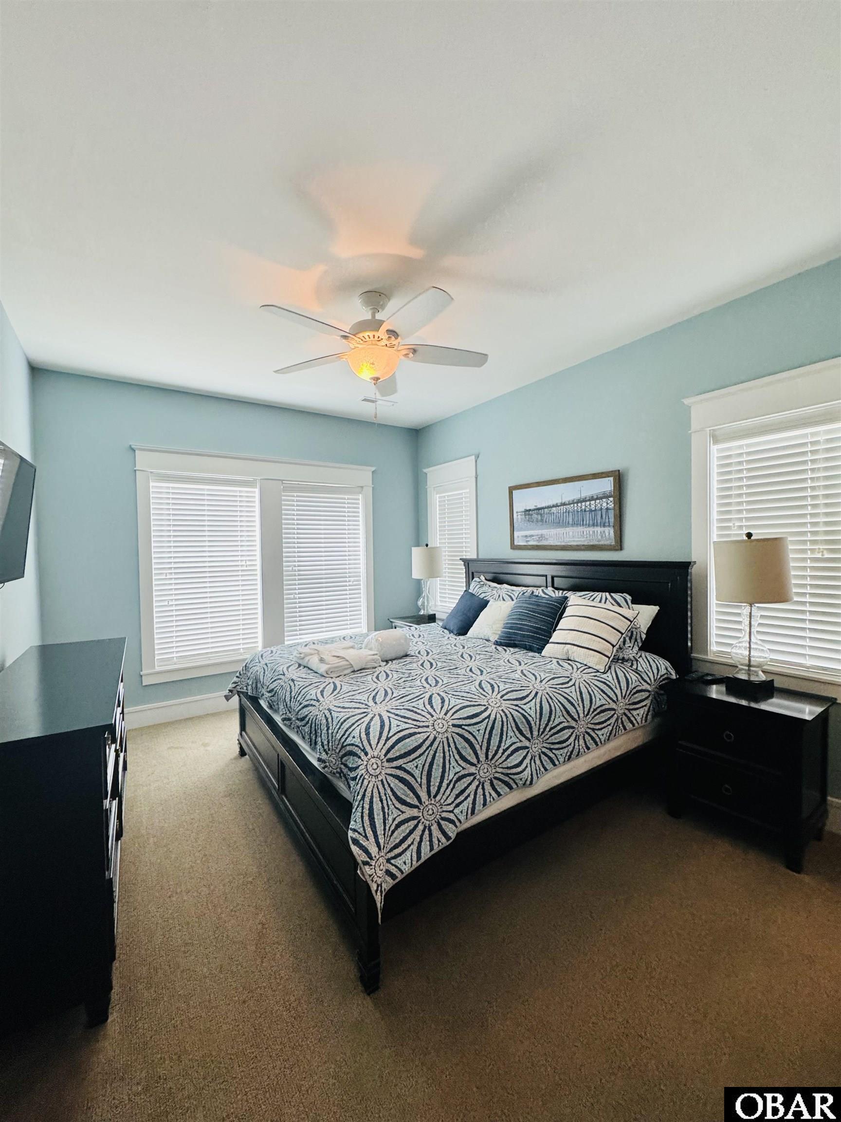 Bedroom with aqua walls, a dark wood bed, patterned bedding, and shuttered windows.