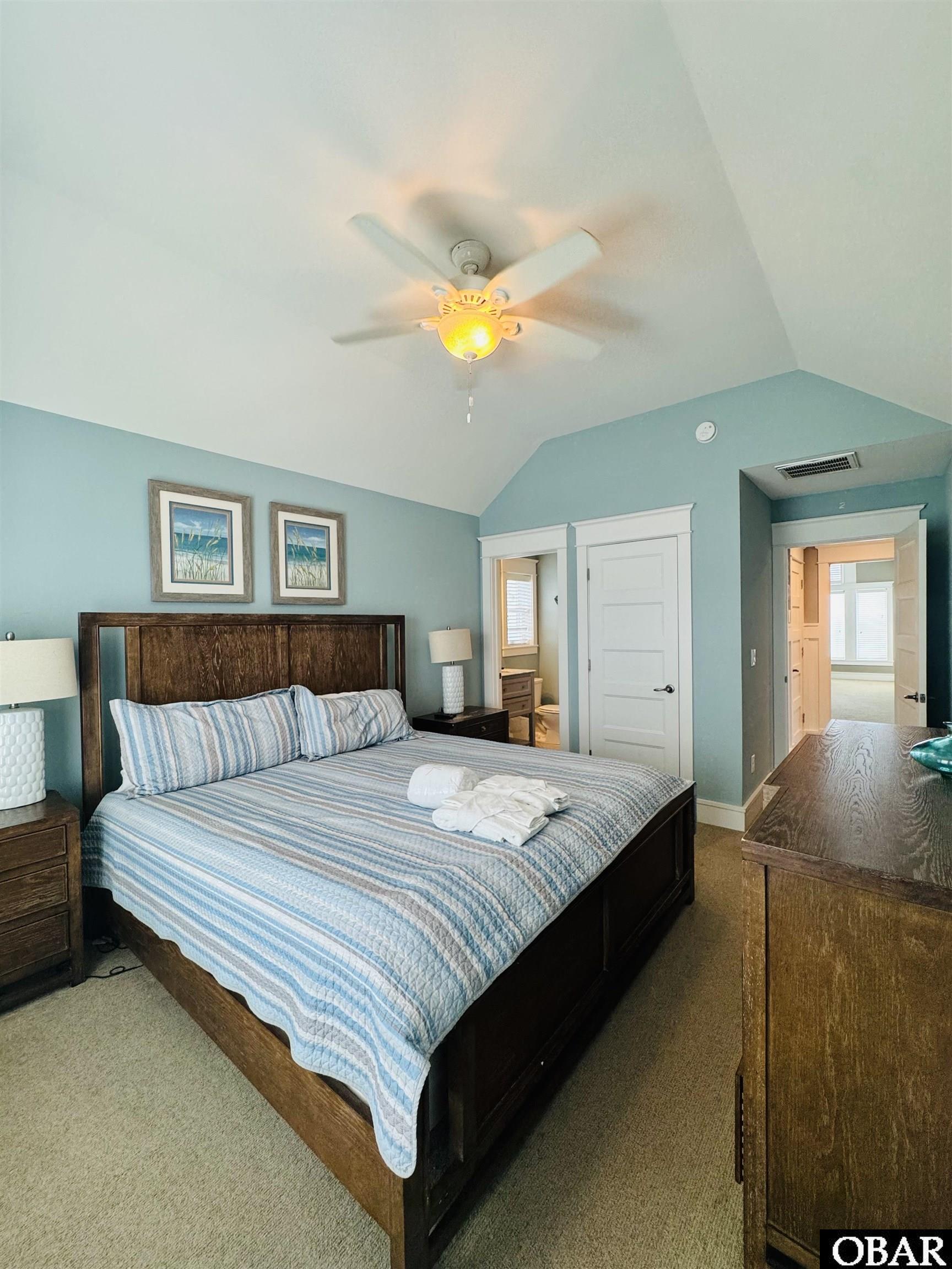 Bedroom with a dark wood bed, striped blue bedding, aqua walls, and a vaulted ceiling.