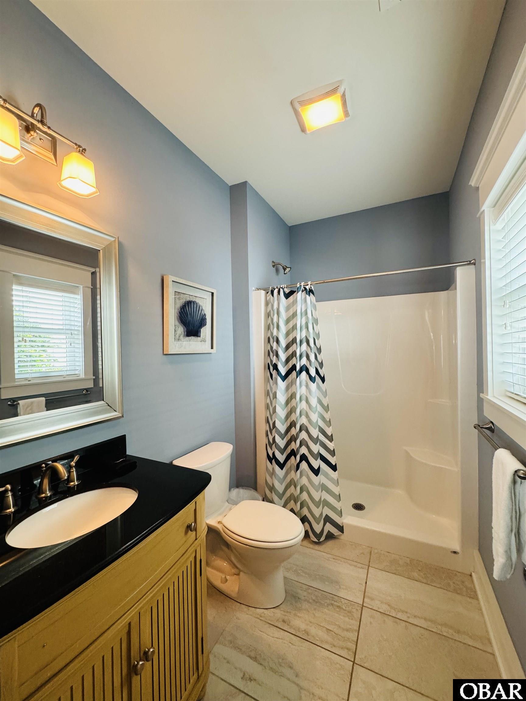 Bathroom with a chevron shower curtain, seashell print, and yellow vanity.