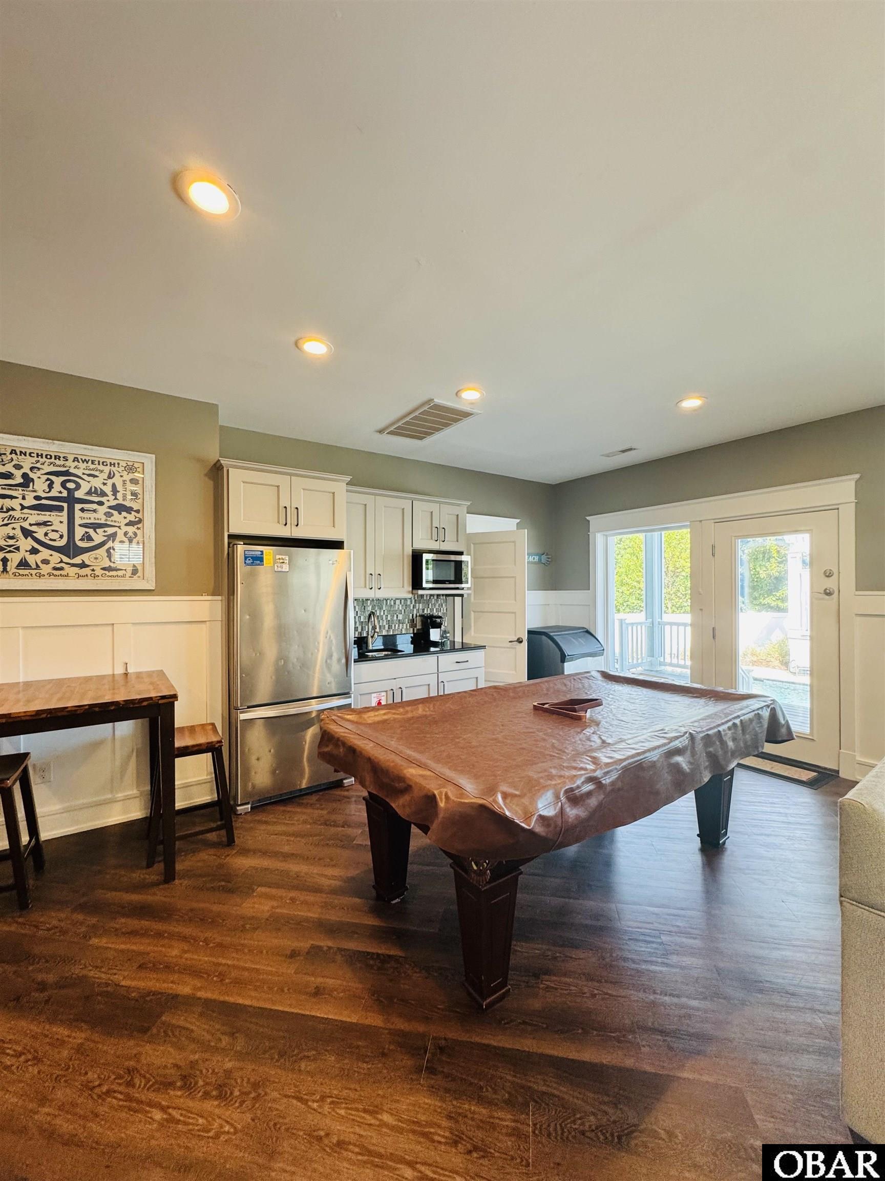 Game room with a covered pool table, kitchenette, and glass doors to the deck.
