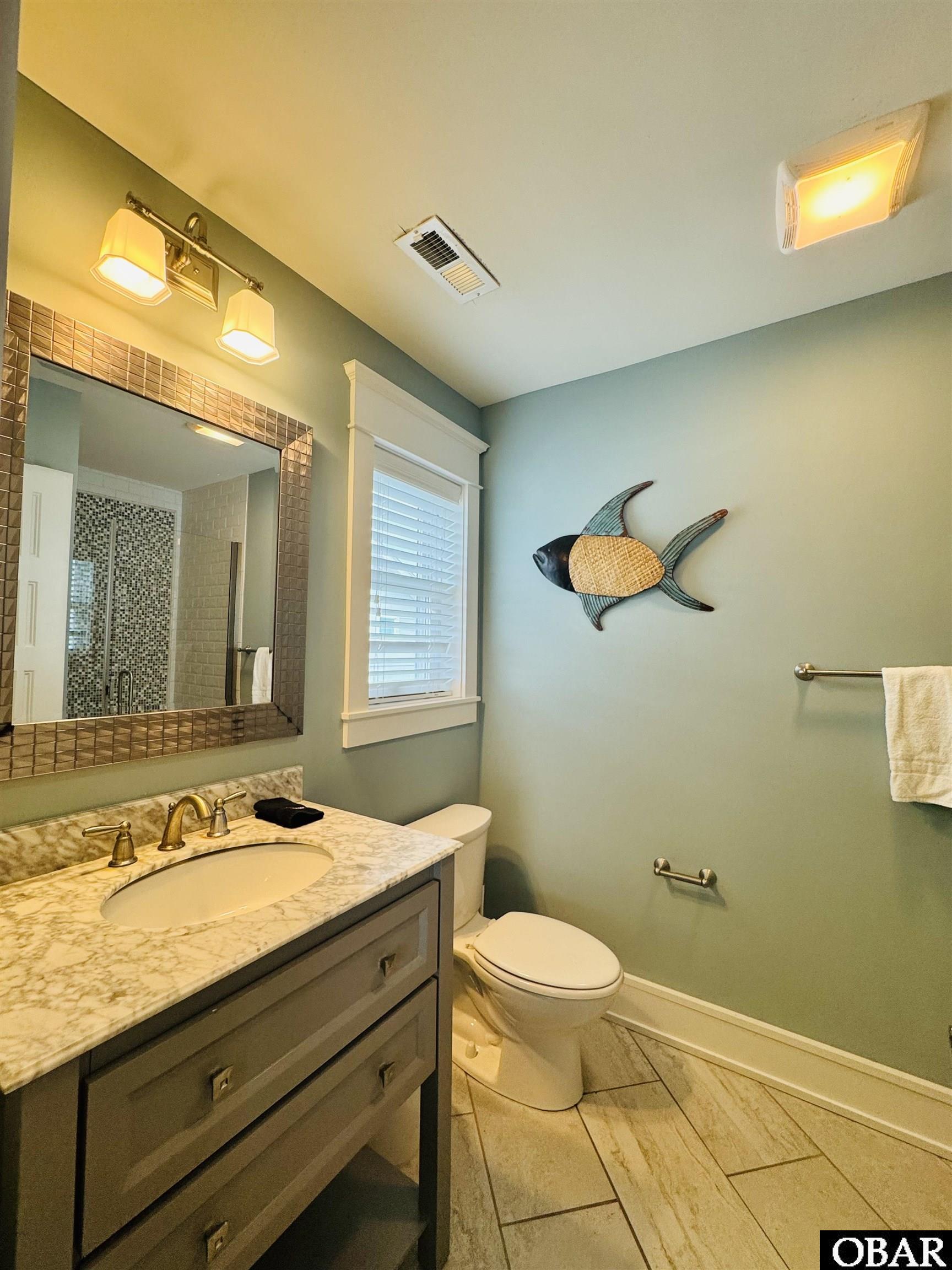 Bathroom with a marble-topped vanity, mosaic-tiled shower, and fish wall decoration.