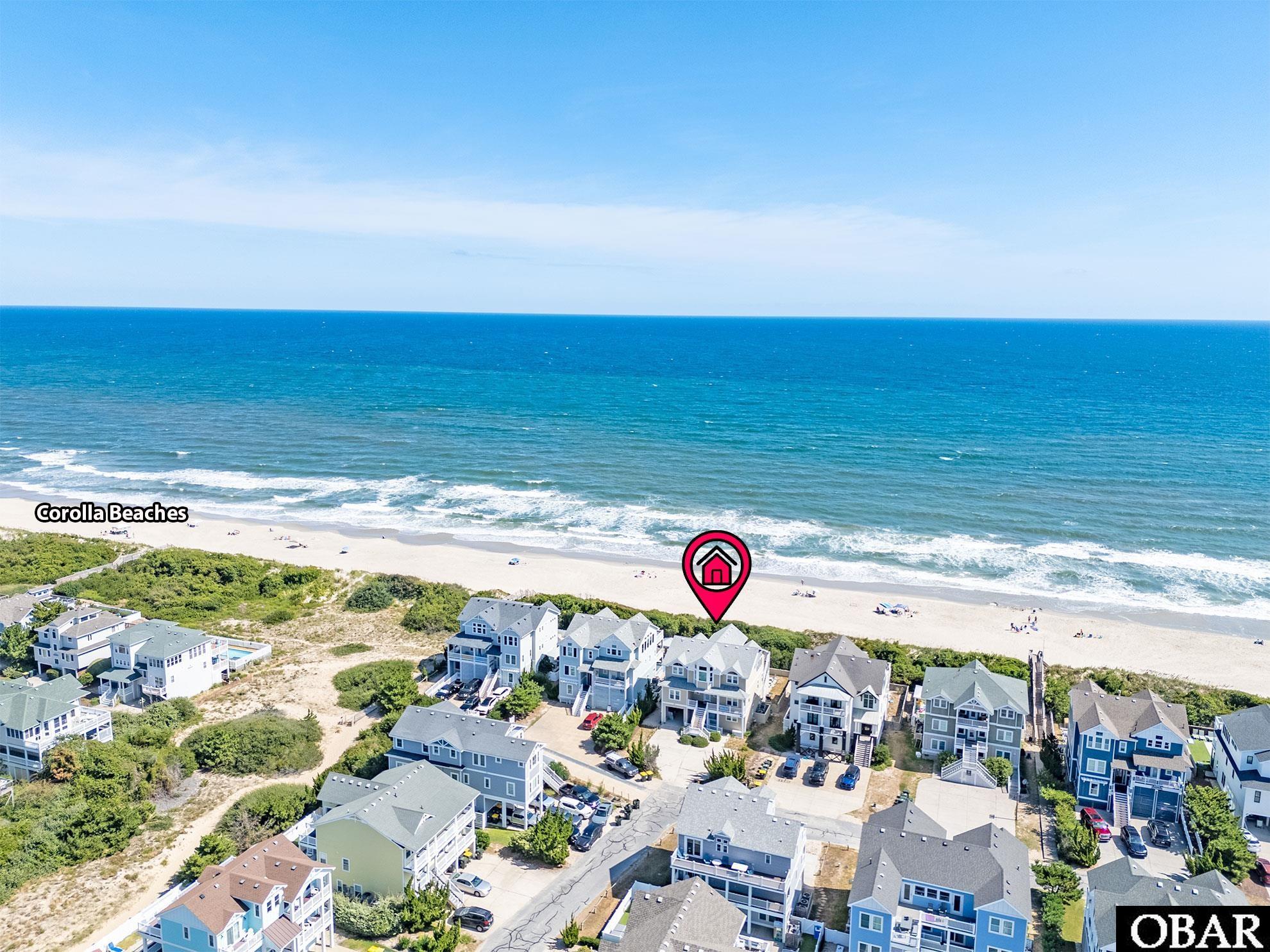 Aerial view of a Corolla beach neighborhood, with a location marker above one home beside the ocean.