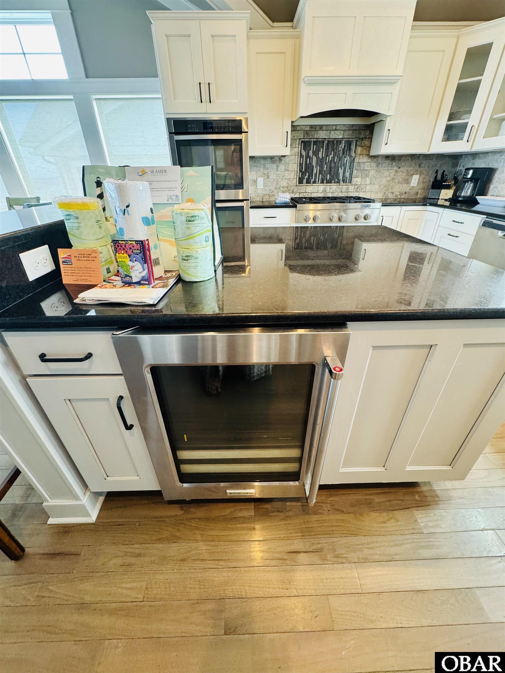 Kitchen with white cabinets, stainless-steel appliances, granite counters, and a large window overlooking the water.