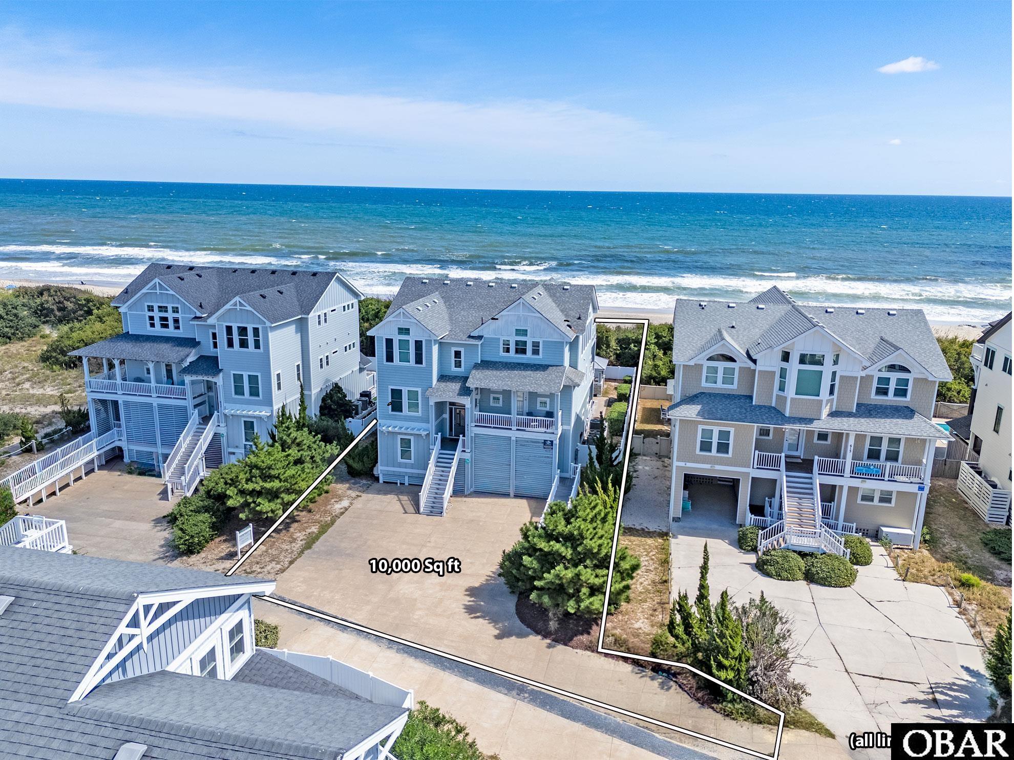 Aerial view of an outlined coastal lot beside a large home, with the ocean and beach behind it.