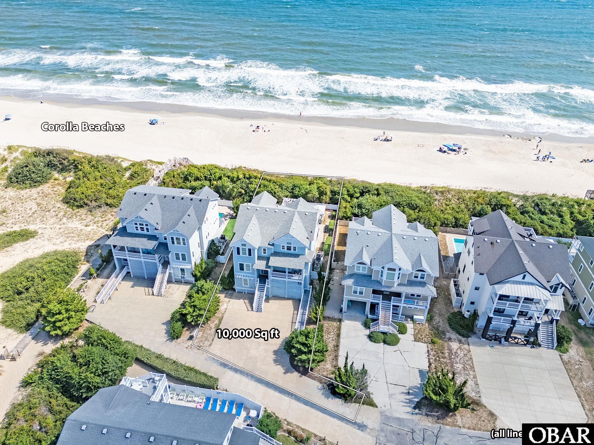 Aerial view of an outlined coastal home lot behind Corolla beach, with ocean and neighboring houses.