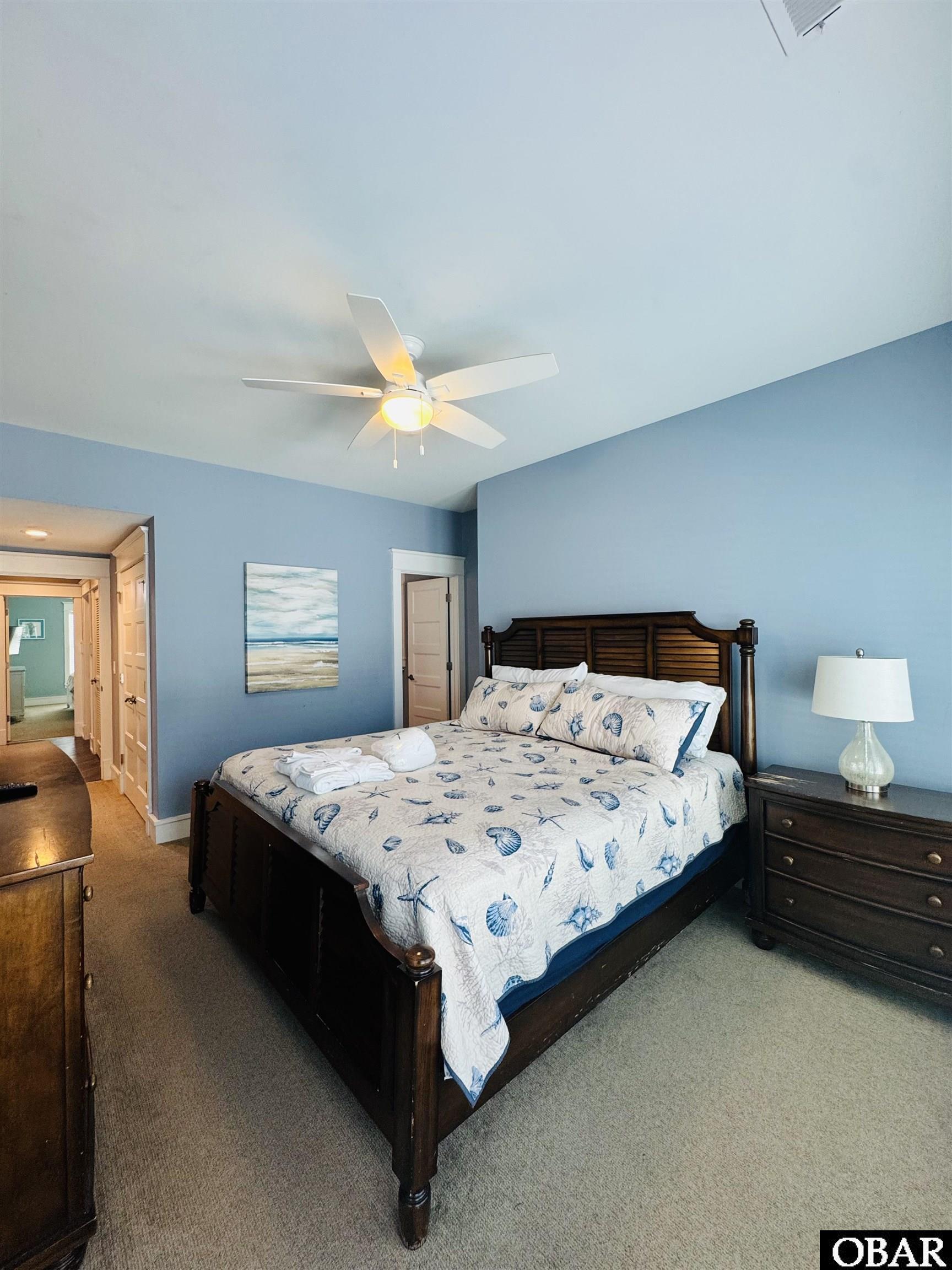 Furnished bedroom with blue walls, a dark wood bed, and shell-patterned bedding.