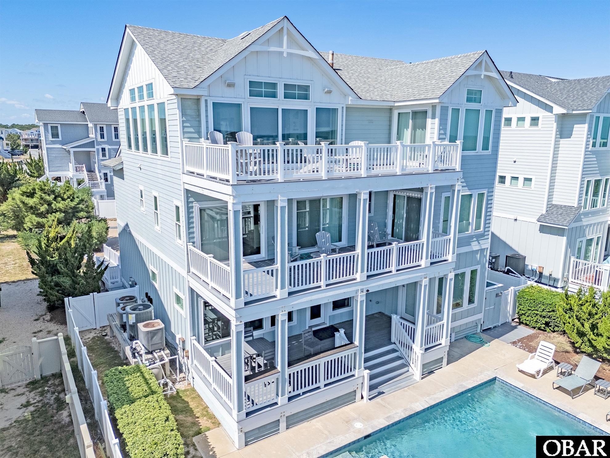 Multi-story coastal home with stacked balconies and a backyard swimming pool.