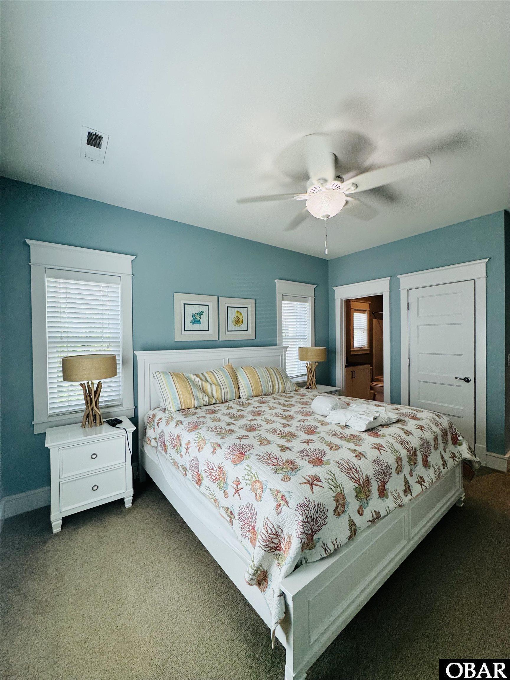 Bedroom with teal walls, white furnishings, and coral-patterned bedding.