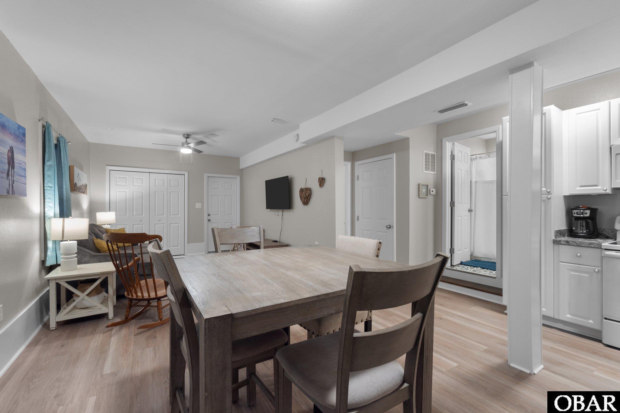 Open-plan dining area with a large wooden table, adjoining living room, and kitchen.