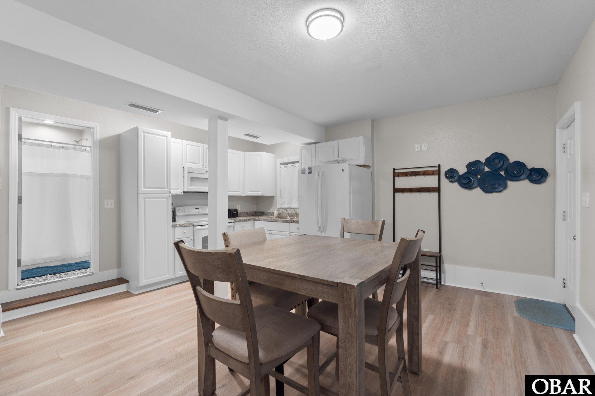 Dining area with a dark wood table beside a white kitchen and blue wall decor.