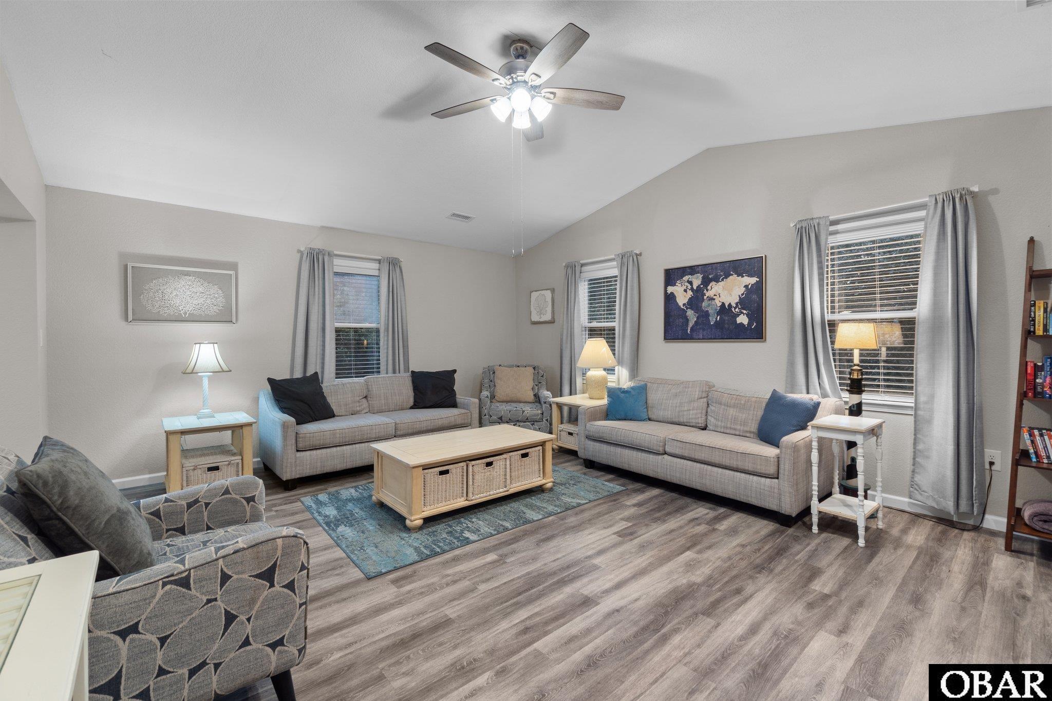 Furnished living room with gray sofas, a blue rug, and a framed world map.