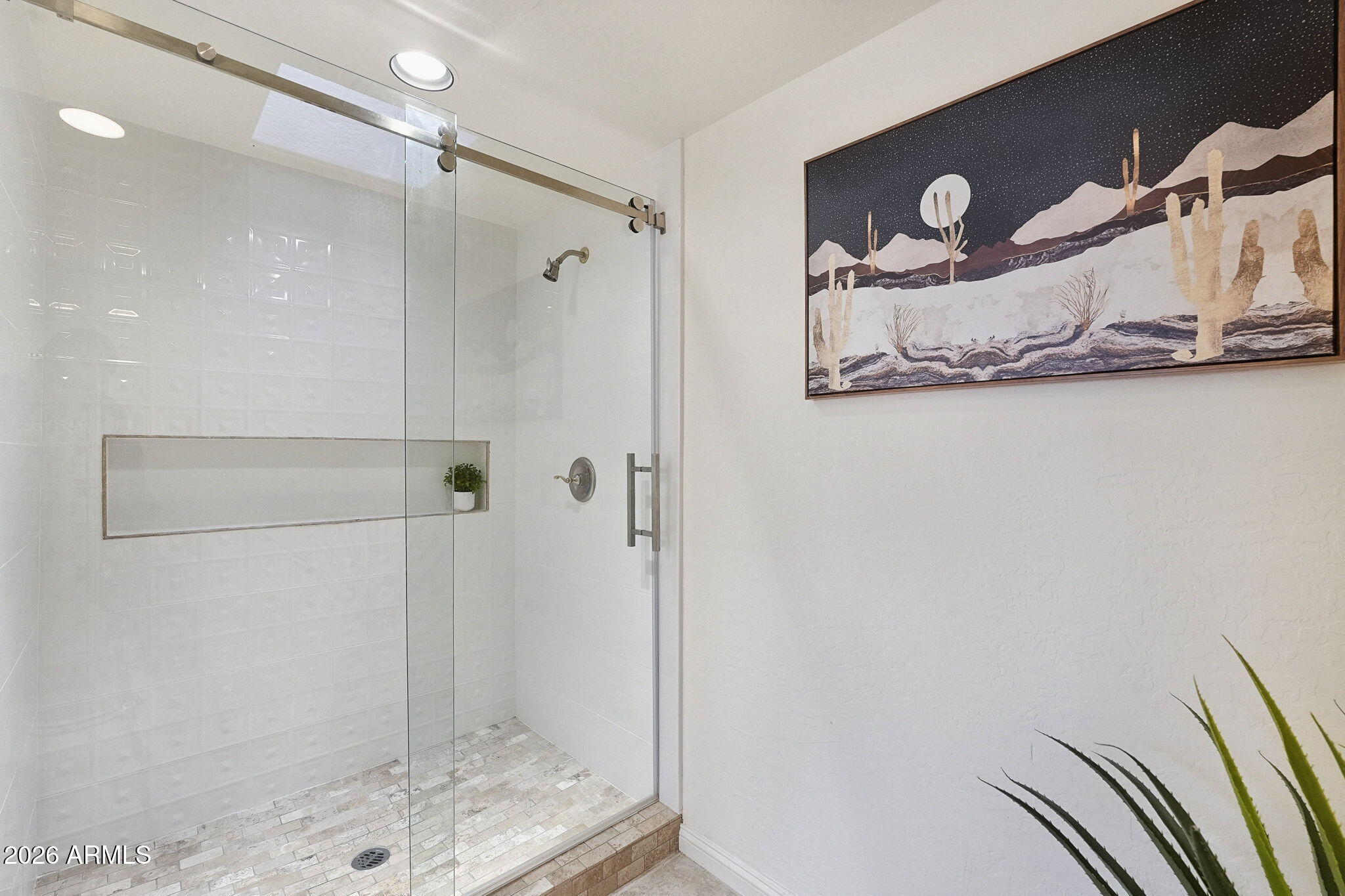 Bathroom with a glass-enclosed tiled shower and framed desert artwork.