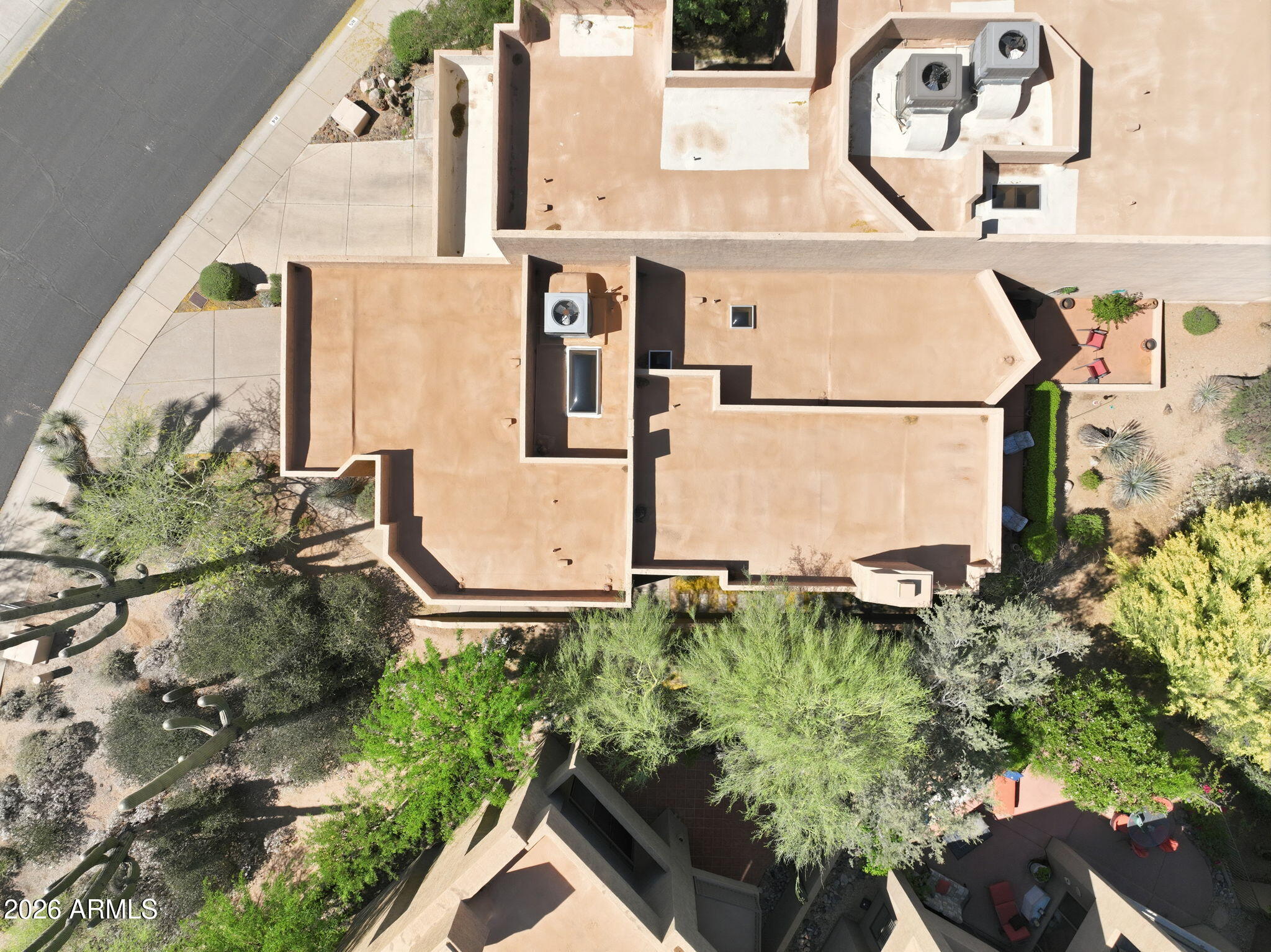 Aerial view of a tan-roofed home surrounded by desert landscaping, with a shaded backyard patio.