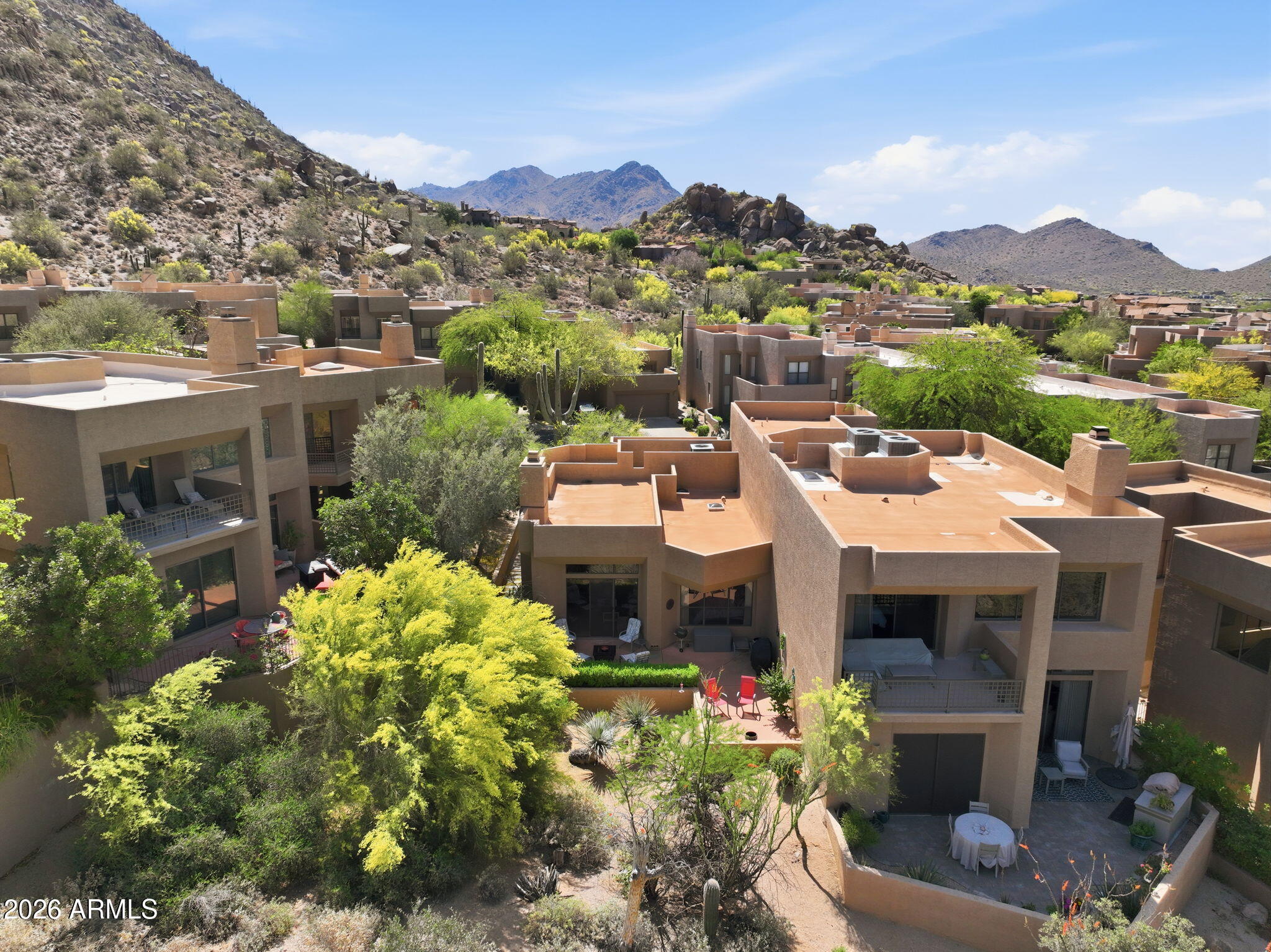 Aerial view of desert homes with private patios and rugged mountains beyond.