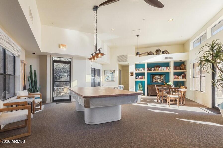 Recreation room with a pool table, turquoise bookshelves, and a dining area.