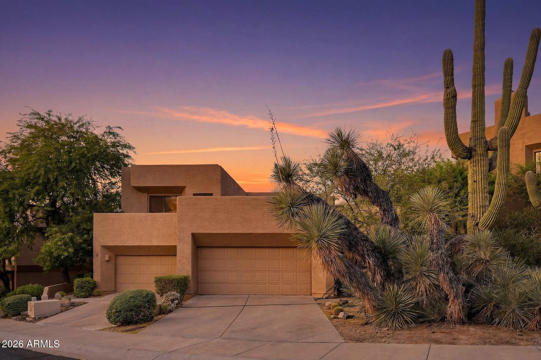 Modern Southwestern home with saguaro cacti and desert landscaping at sunset.