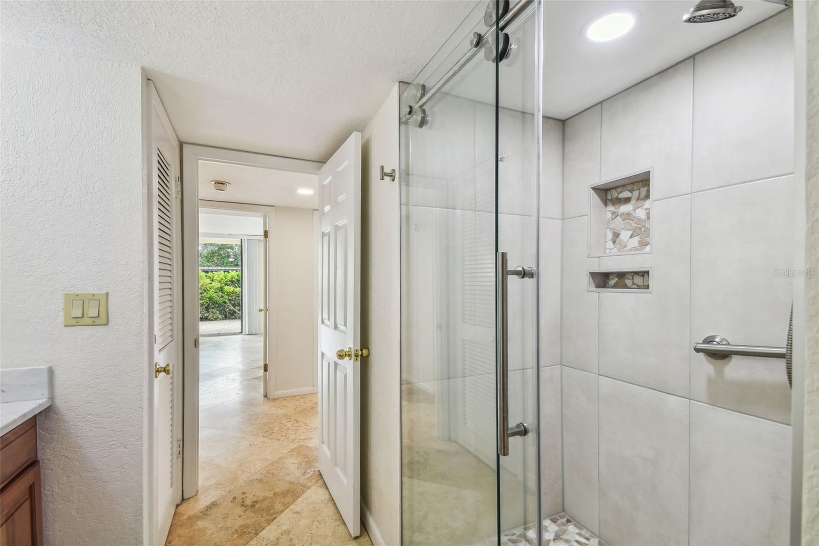 Bathroom with a glass-enclosed tiled shower and decorative mosaic niches.