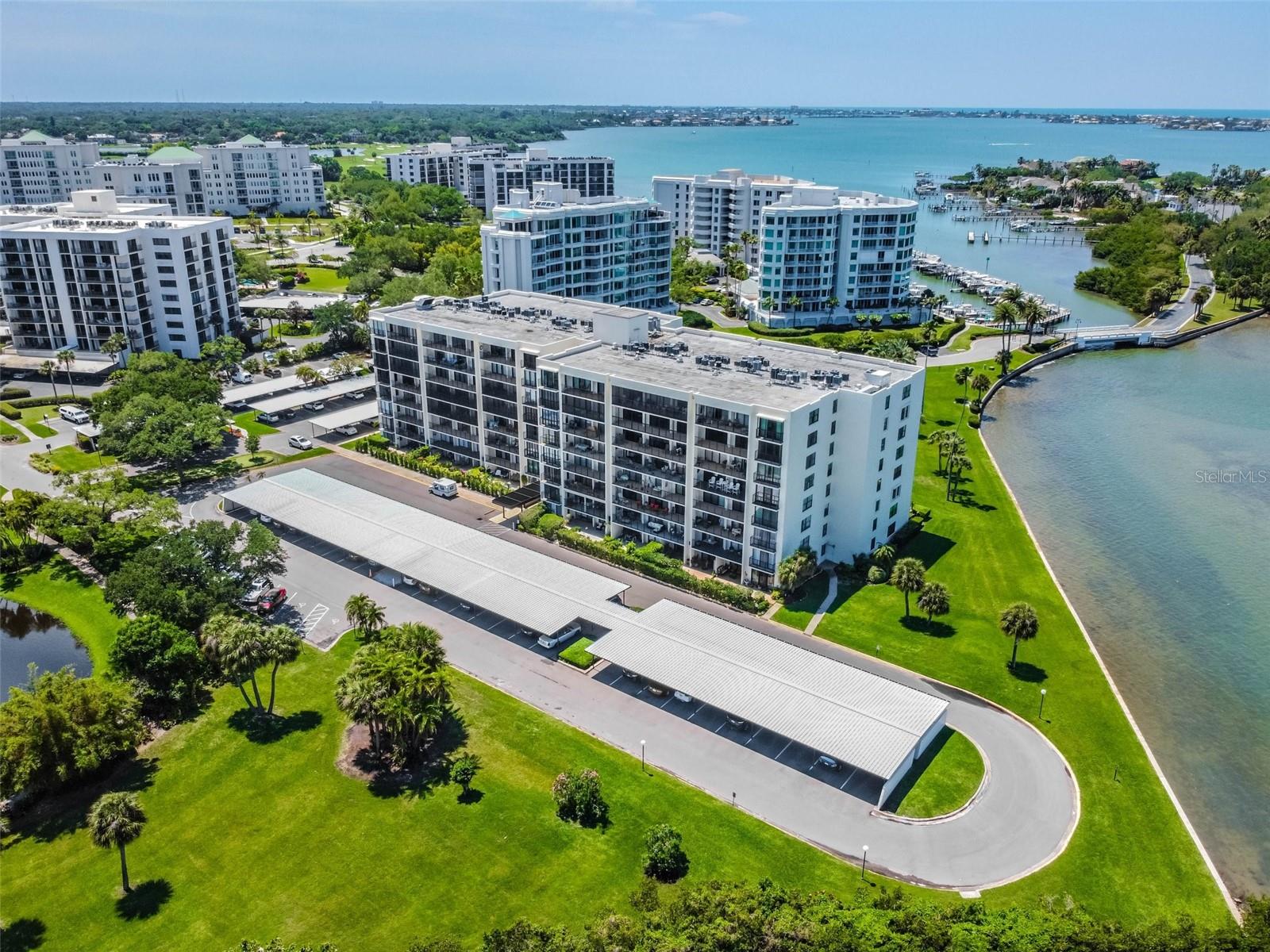 Aerial view of waterfront condominium buildings, marina, and landscaped grounds.