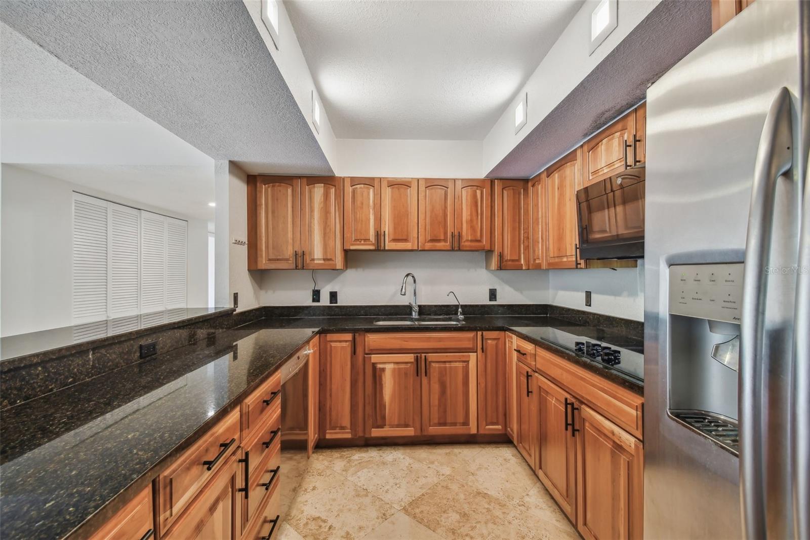 Kitchen with warm wood cabinets, dark granite counters, and stainless steel appliances.