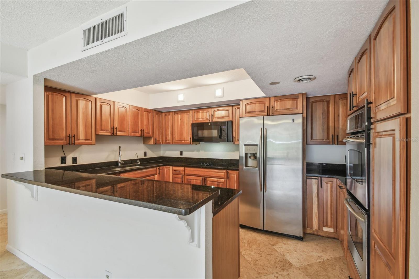 Kitchen with wood cabinets, dark granite counters, and stainless steel appliances.