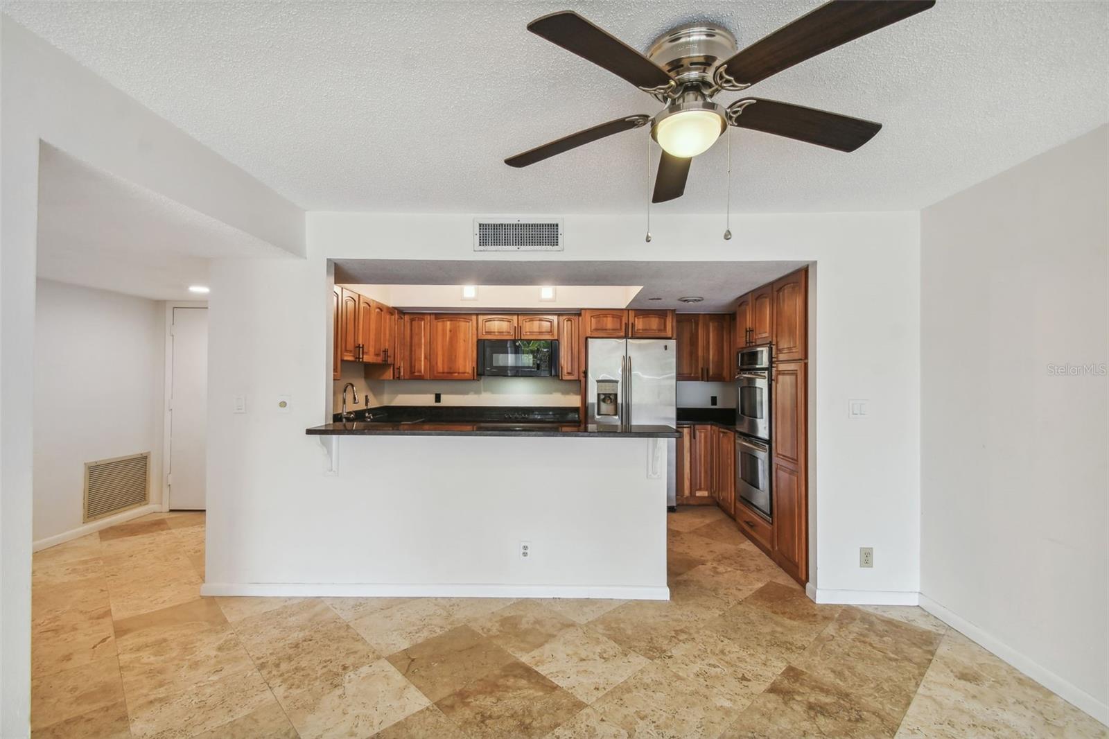 Kitchen with warm wood cabinetry, a granite breakfast bar, and tiled flooring.